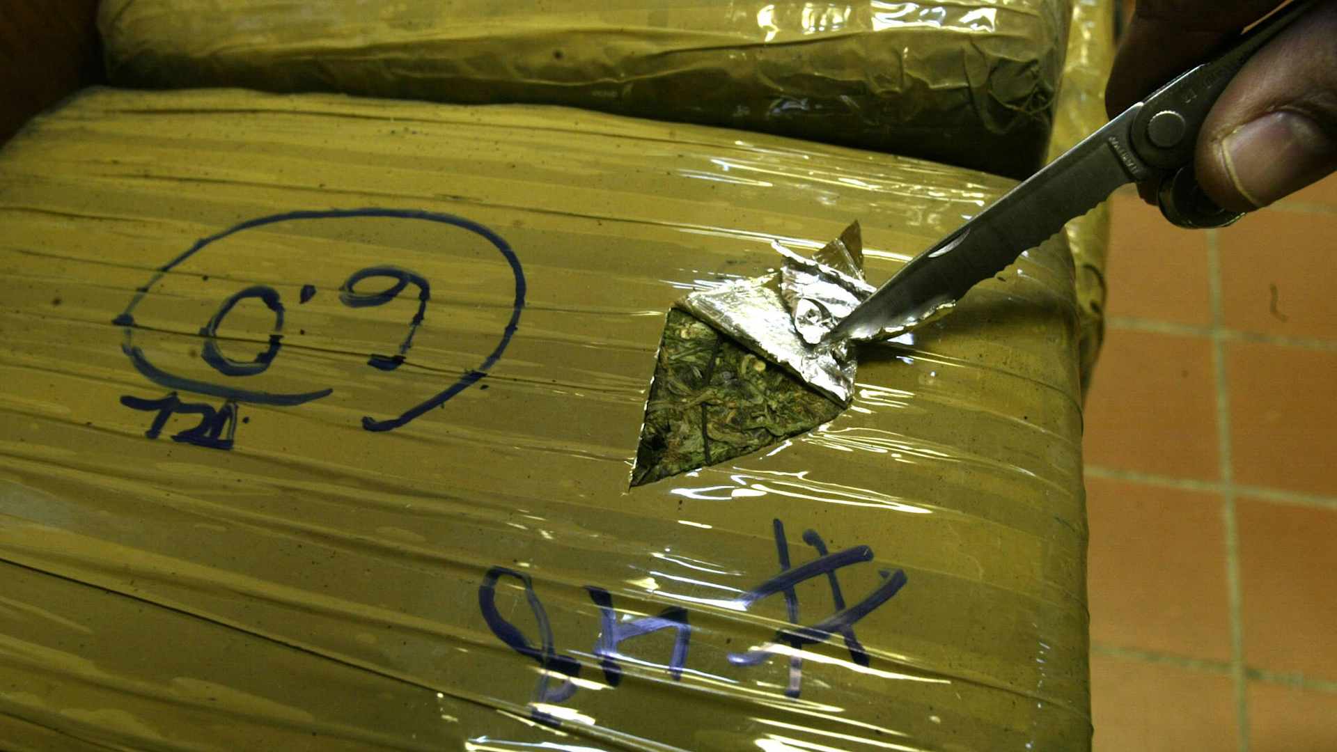 A Border Patrol agent cuts open a bag of marijuana smuggled across the U.S.-Mexico border, February 05, 2003.