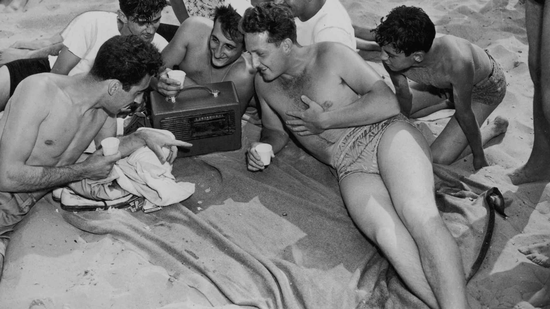A group of young people listening to a portable radio on the beach at Coney Island, New York, July 1947.