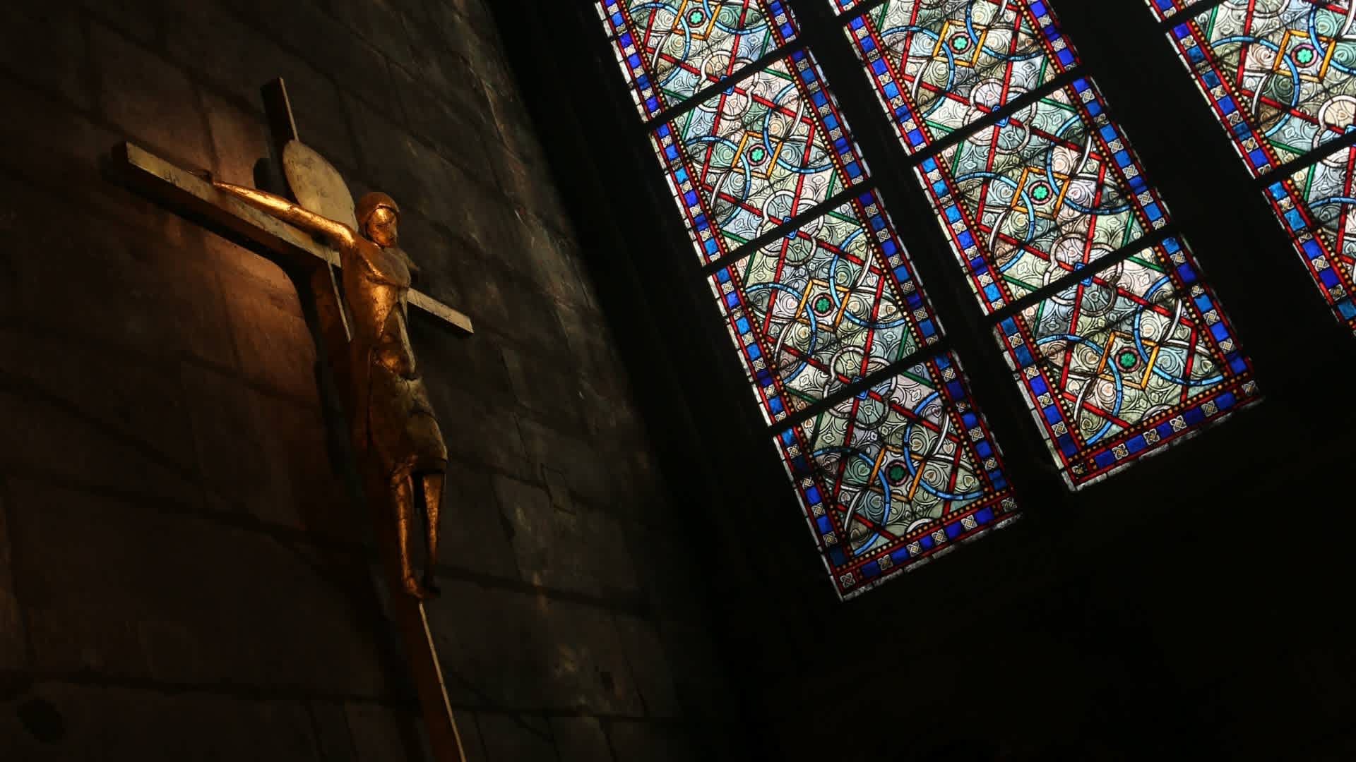 Statue of Jesus Christ on the crucifix by a stained glass window inside Notre-Dame Cathedral, Paris. (Credit: Waring Abbott/Getty Images)