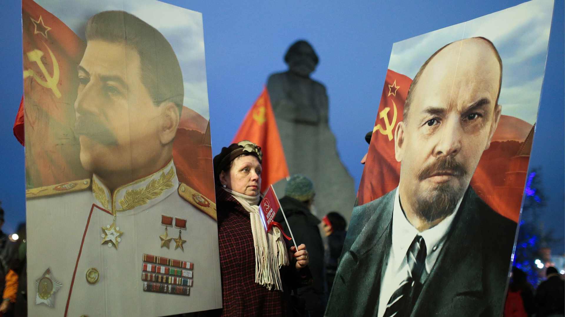 A woman is flanked by portraits of Soviet leaders Joseph Stalin and Vladimir Lenin. Lenin was the USSR's first ruler; Stalin served the longest.
