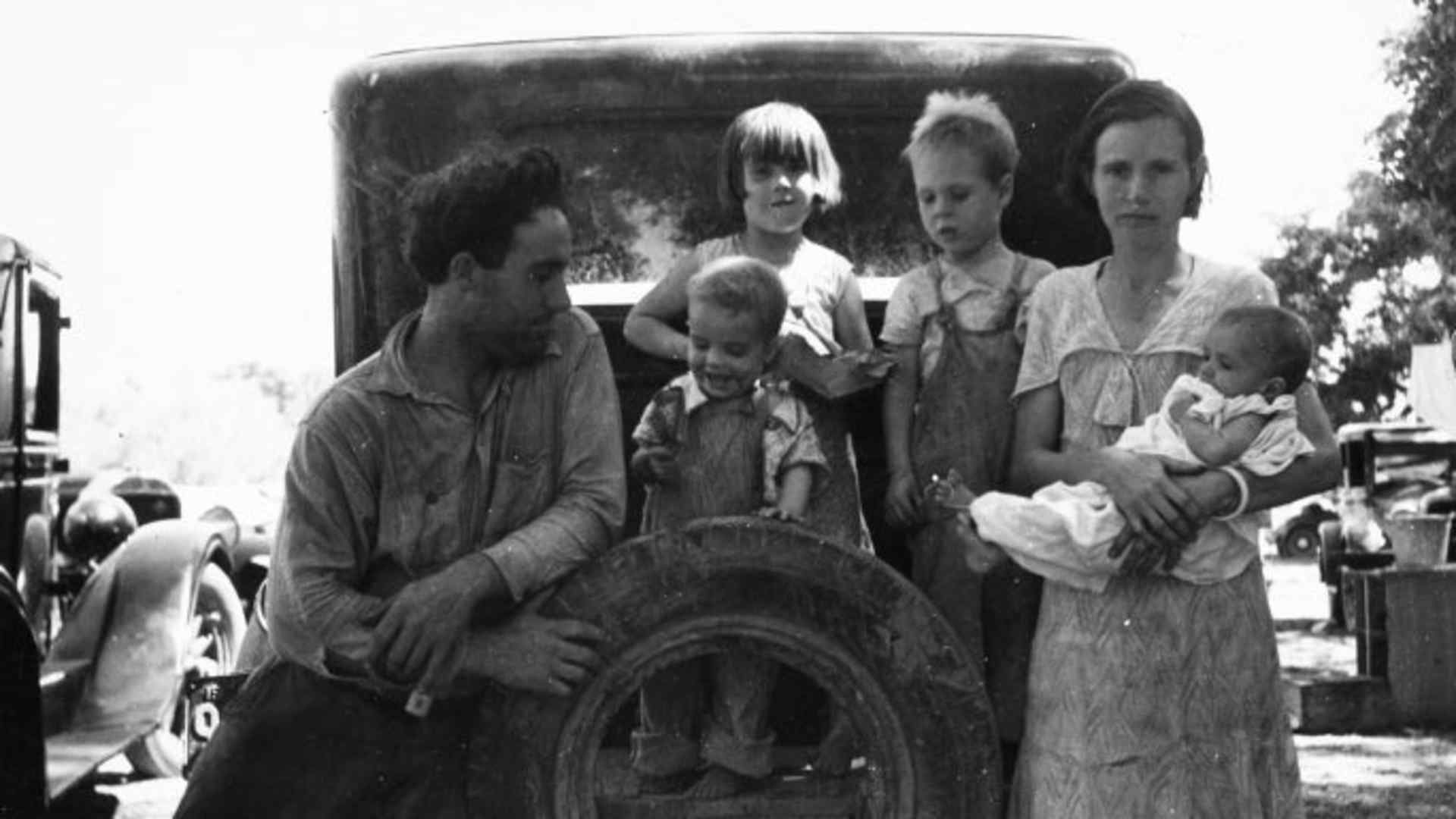 A migrant worker with his wife and four small children, resting on the back of a car in Marysville, California, 1935. (Credit: Smith Collection/Gado/Getty Images)