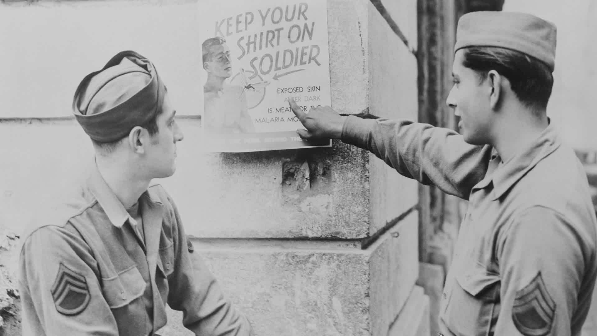 U.S. soldiers Marvin Hareth (left) and Eoribeto Quindanilla read a poster circulated in a southern Italian town during World War II to remind U.S. forces to refrain from removing their shirts as a protection from mosquito bites. This is one of the many steps taken in an educational program to control the spread of malaria.
