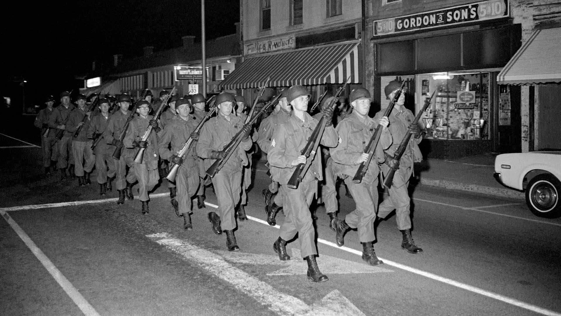 National Guardsmen with rifles and fixed bayonets march outside South Carolina State College following the Orangeburg Massacre