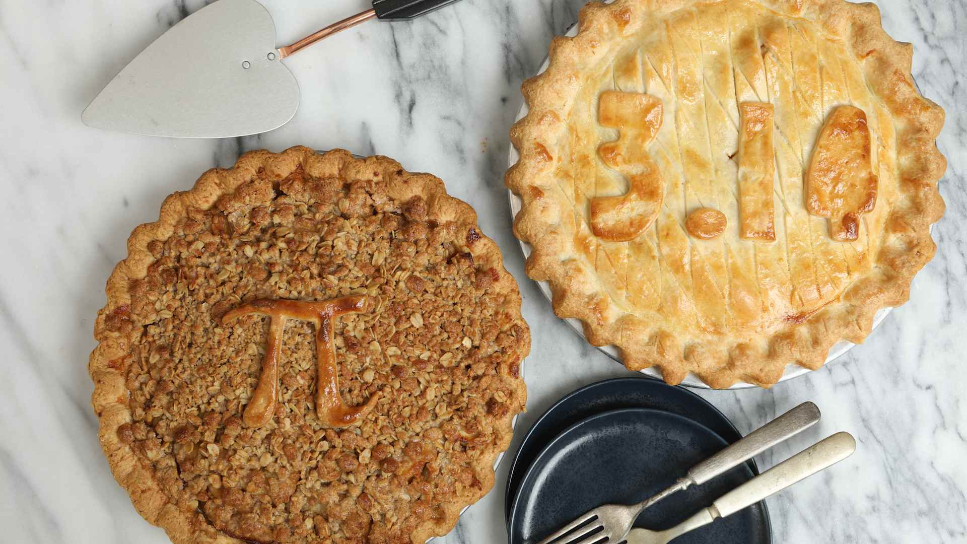 An overhead close up horizontal photograph of two Pi Pies, one displays the π symbol itself and the other one shows the value of 3.14. The pies were baked to commemorate March the 14th as Pi Day.