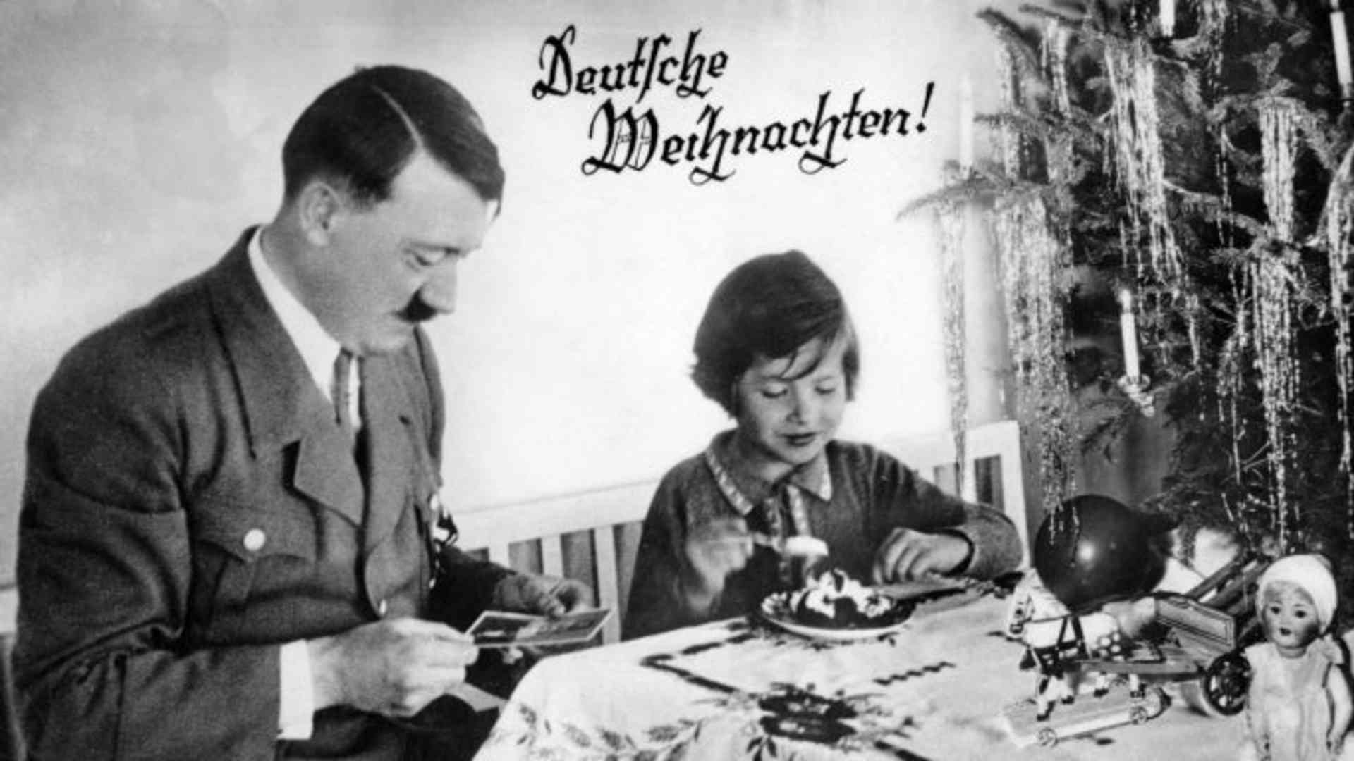 Adolf Hitler with a child on a card that reads 'Deutsche Weihnachten!', meaning 'German Christmas!'. (Credit: Culture Club/Getty Images)