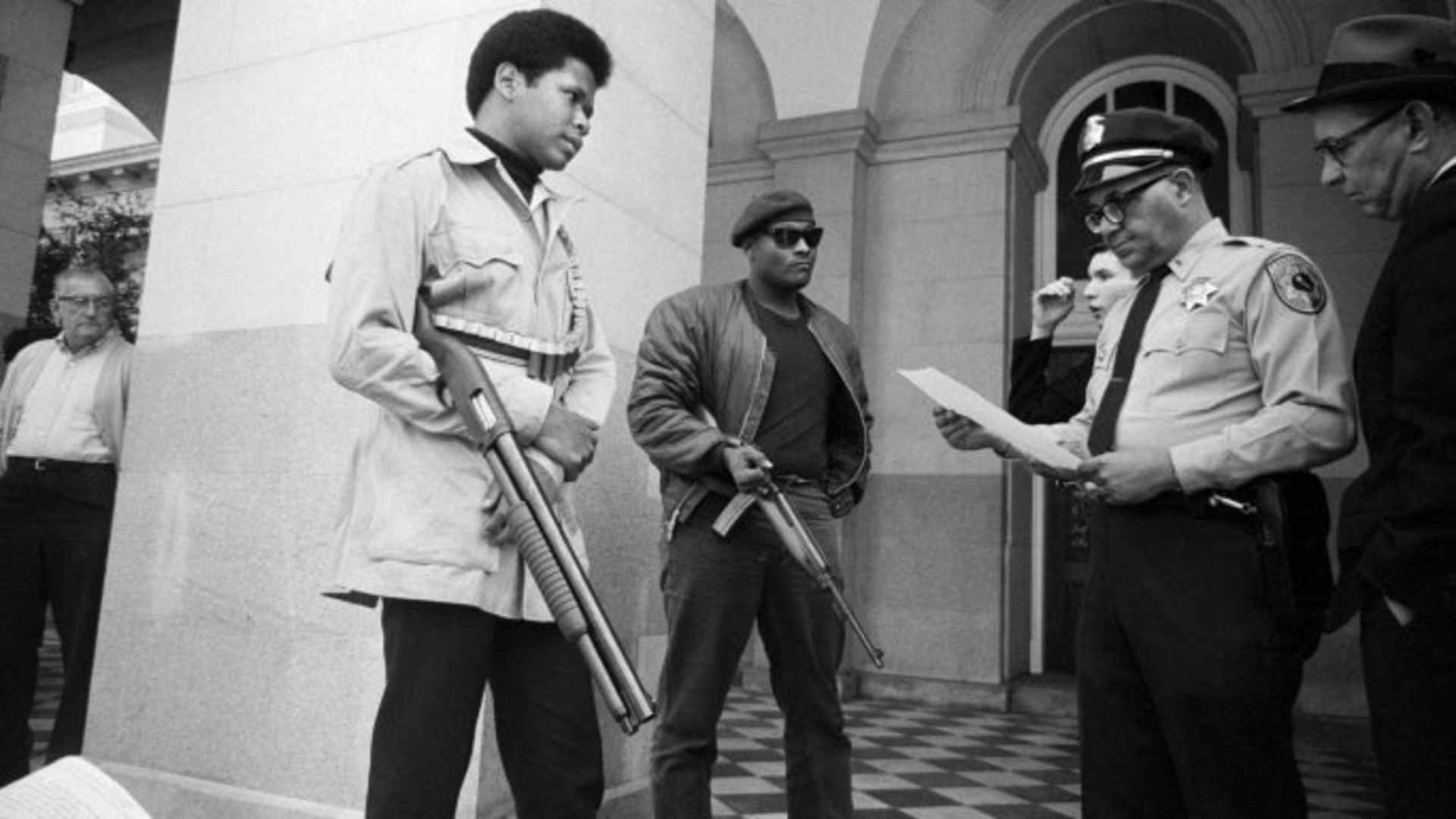Two members of the Black Panther Party are met on the steps of the State Capitol in Sacramento, May 2, 1967, by Police Lt. Ernest Holloway, who informs them they will be allowed to keep their weapons as long as they cause no trouble and do not disturb the peace.