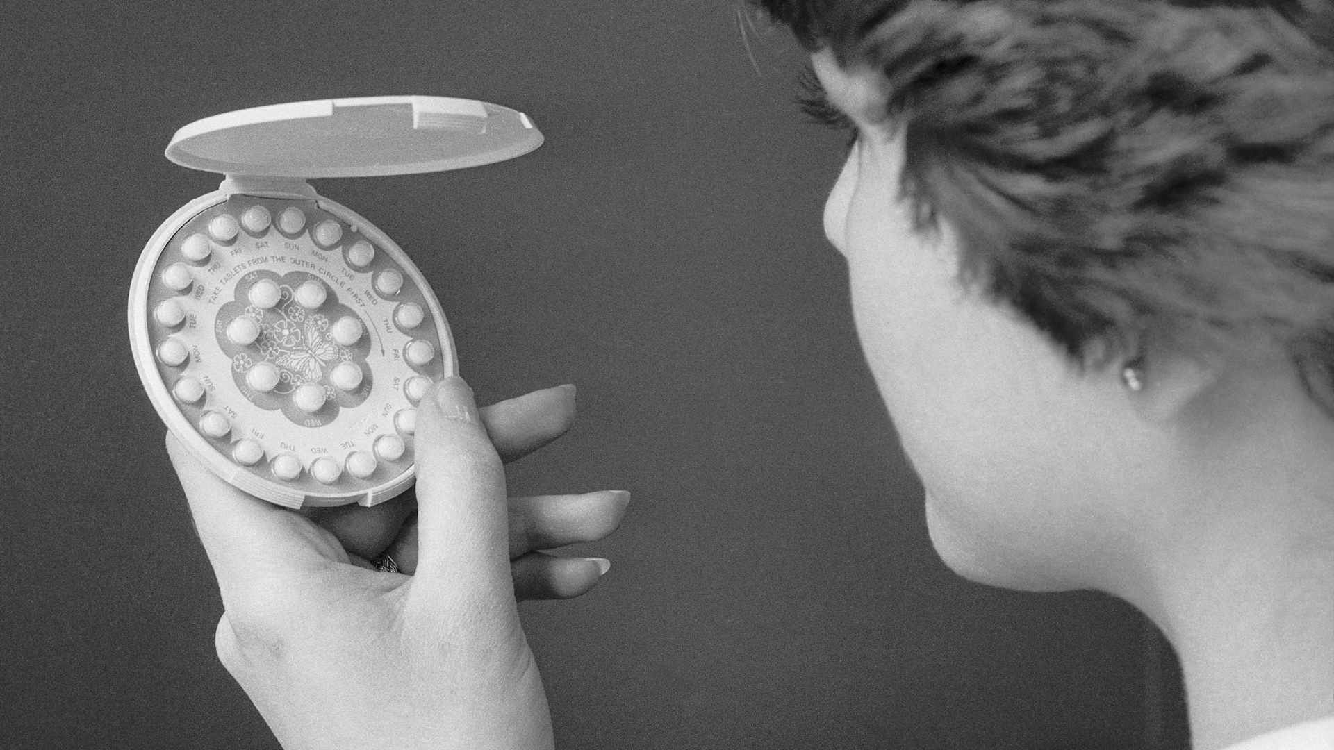 A 1976 photo of a woman holding a pack of birth control pills.