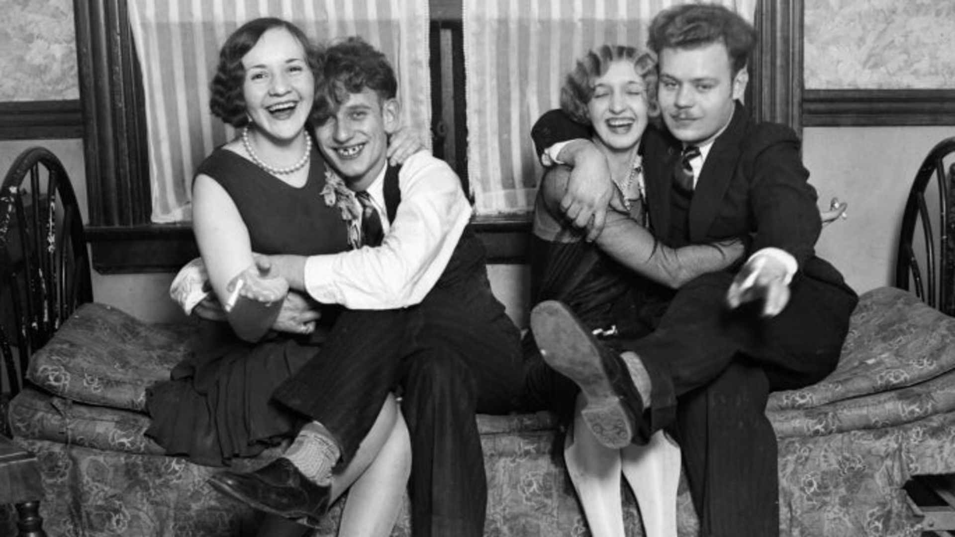 Two flapper women and their dates having a smoke