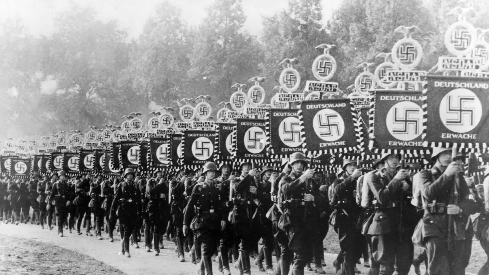 Marching SS Men Row upon row of SS members march down a road during the 1933 Nuremberg rally. The troops carry military standards with swastikas and the motto "Deutschland Erwache" (i.e. "Germany Awake").. (Photo by © CORBIS/Corbis via Getty Images)