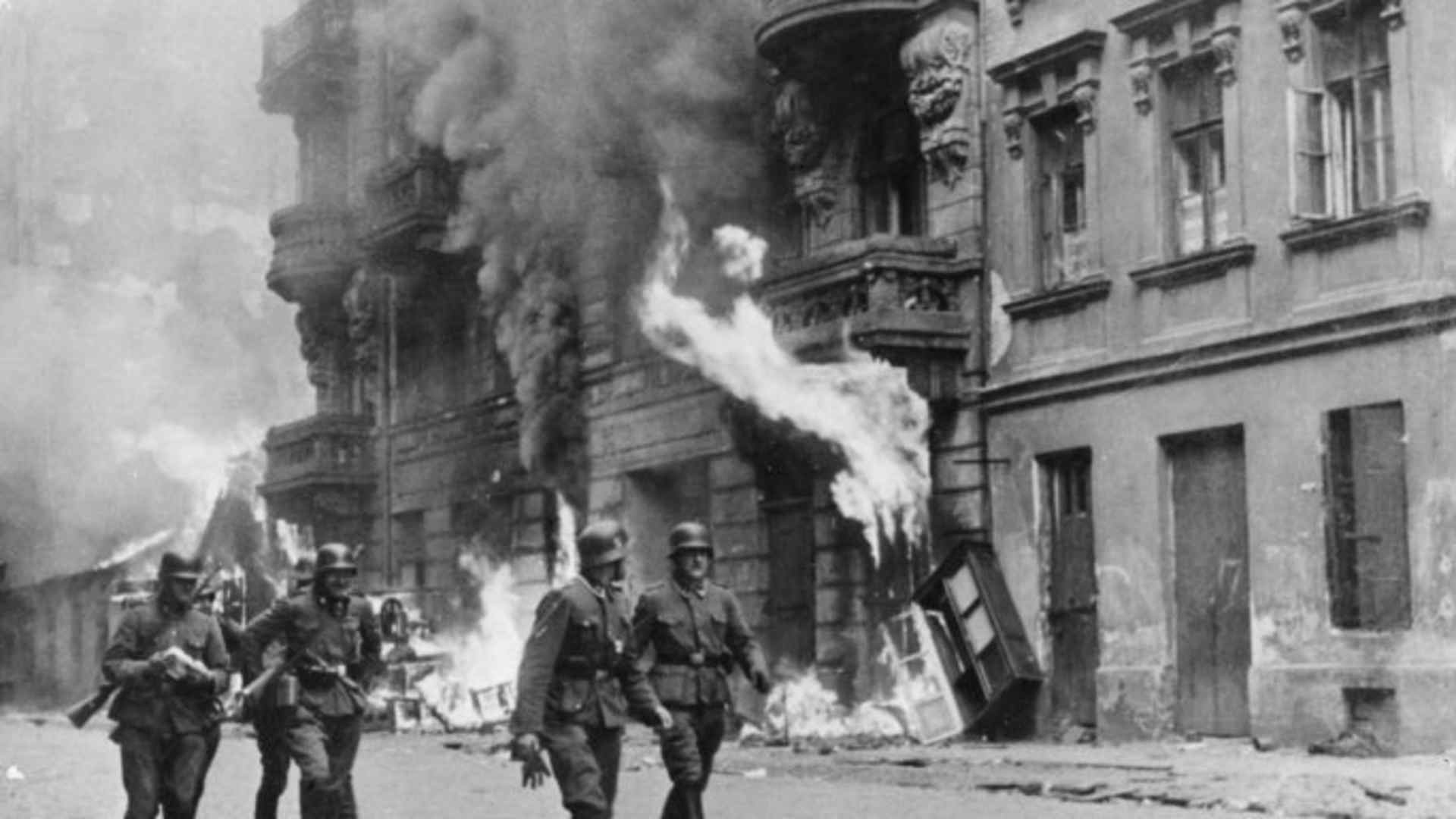 German soldiers walking by fires set in the Warsaw Ghetto, which was burned to the ground after the uprising in 1943. (Credit: Sovfoto/UIG via Getty Images)