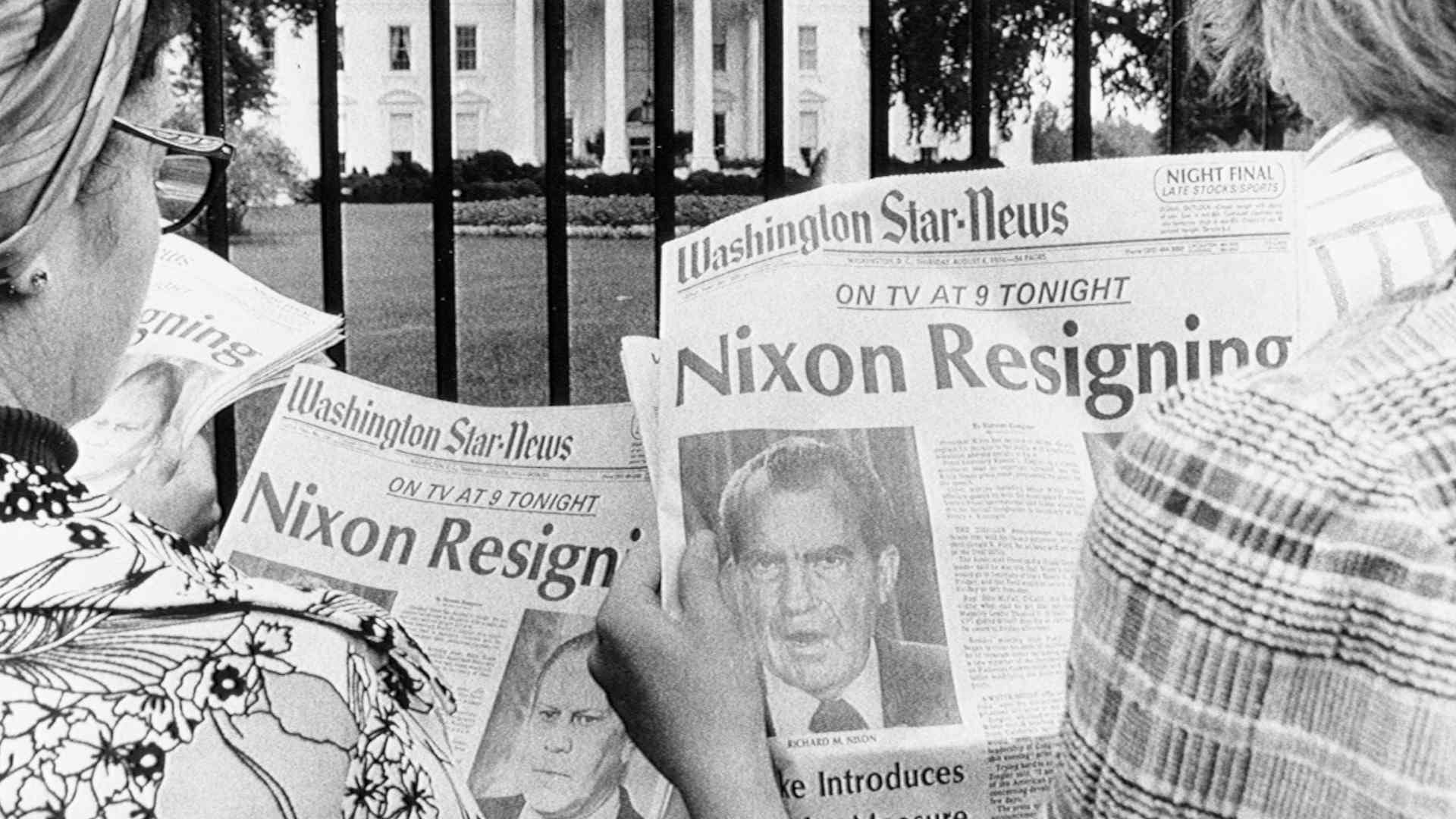 (Original Caption) 8/8/1974-Washington, DC- Newspaper headlines being read by tourists in front of the White House tell of history in the making. It is said to be imminent that President Nixon will become the first President of the country to resign. He will address a nationwide TV audience tonight.