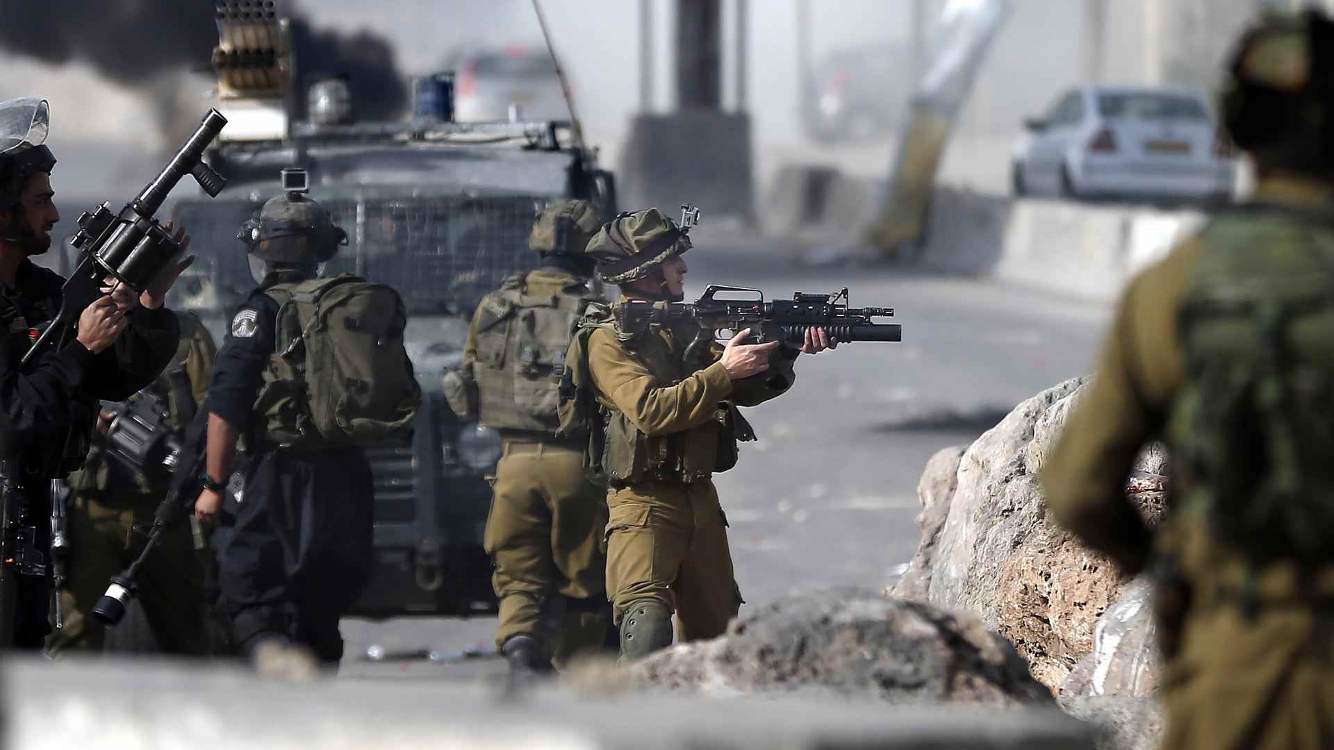 PALESTINIAN-ISRAEL-CONFLICTIsraeli security forces aim their weapons at Palestinian protesters during clashes near the Israeli Qalandia checkpoint, between the West Bank city of Ramallah and Jerusalem, on November 14, 2014, following a demonstration to protest against Israeli authorities allowing settlers to enter the Al-Aqsa mosque compound and Israel imposing restrictions on Muslims wishing to perform Friday prayers at Al-Aqsa Mosque. Israel eased restrictions at Jerusalem's Al-Aqsa mosque after US Secretary of State John Kerry announced agreement on steps to reduce tensions at the flashpoint compound. AFP PHOTO / THOMAS COEX (Photo credit should read THOMAS COEX/AFP via Getty Images)