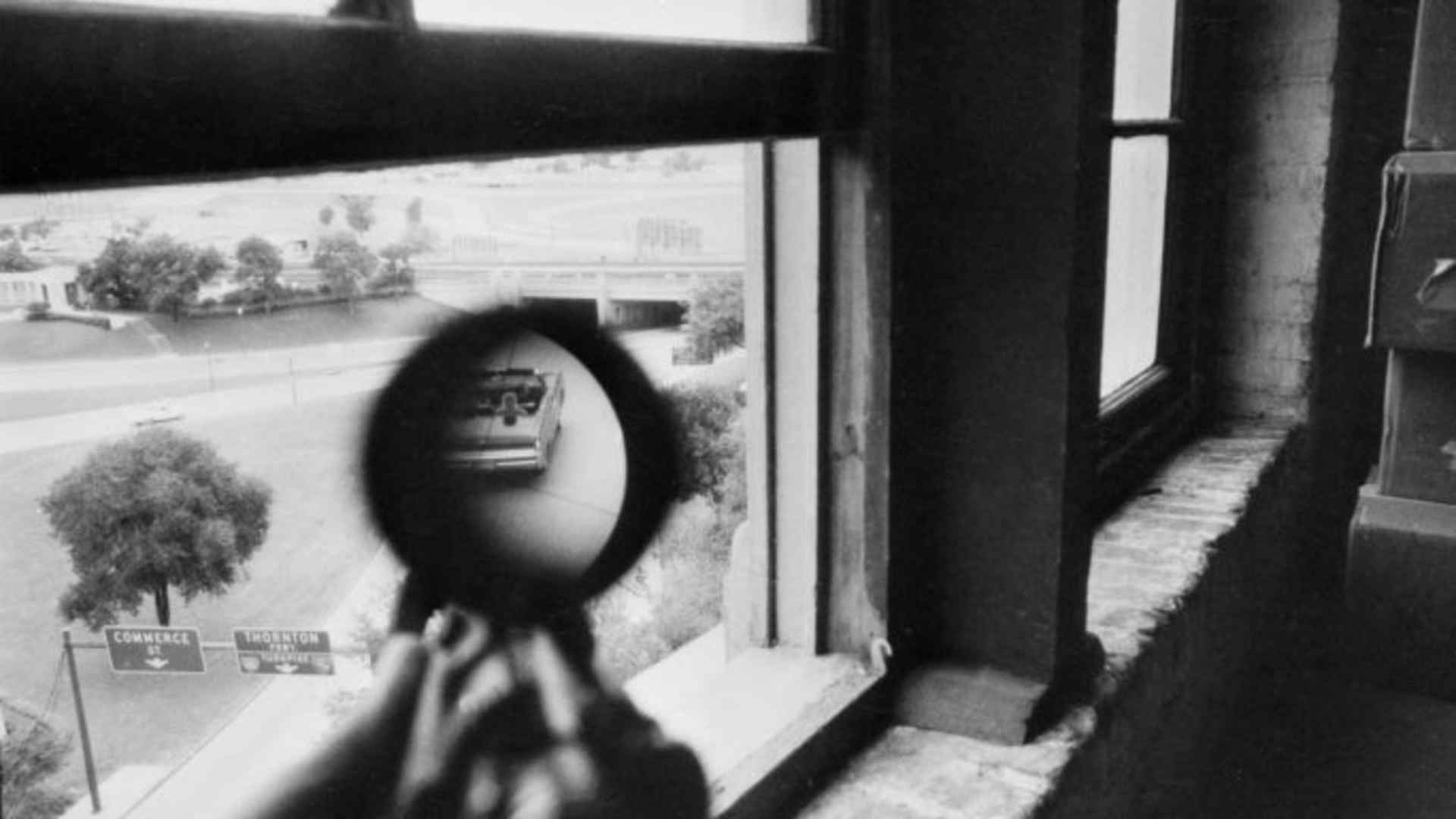 A view through a rifle scope aimed from the window of the Texas Schoolbook Depository shows a convertible car during a Warren Report story in 1967. (Credit: CBS Photo Archive/Getty Images)
