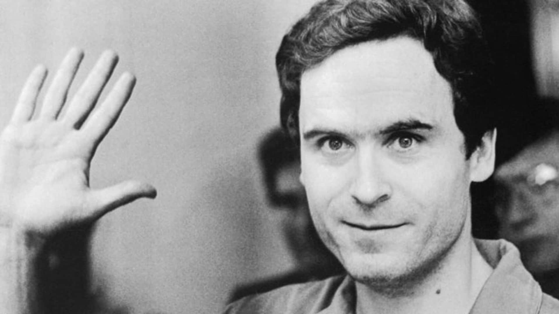 Serial Murderer Theodore "Ted" Bundy walks forward and waves to TV camera as his indictment for the January murders of Lisa Levy and Margaret Bowman is read at the Leon County Jail.