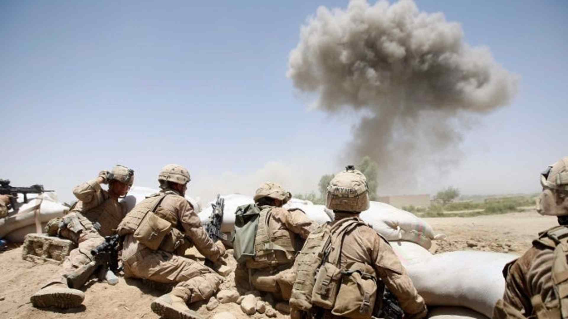 U.S. Marines from 2nd Marine Expeditionary Brigade, RCT 2nd Battalion 8th Marines Echo Co. take cover as a 500 lb bomb explodes on a compound after the Marines took two days of enemy fire from the position in Main Poshteh, Afghanistan, 2009. (Credit: Joe Raedle/Getty Images)