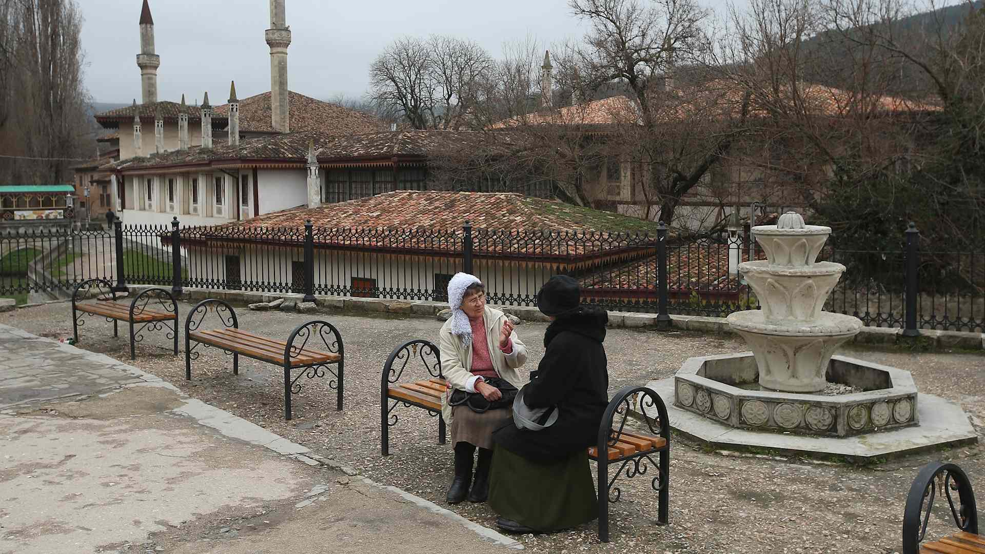 Two women chat next to a fountain next to the Khan's Palace, also called Hansaray, in Crimea on March 9, 2014 in Bakhchysarai, Ukraine. Bakhchysarai was the capital of the Crimean Khanite, the state of Crimean Tatars, for more than three centuries. Since Russia annexed the territory from Ukraine in 2014, Tatars have come under increasing pressure to leave.