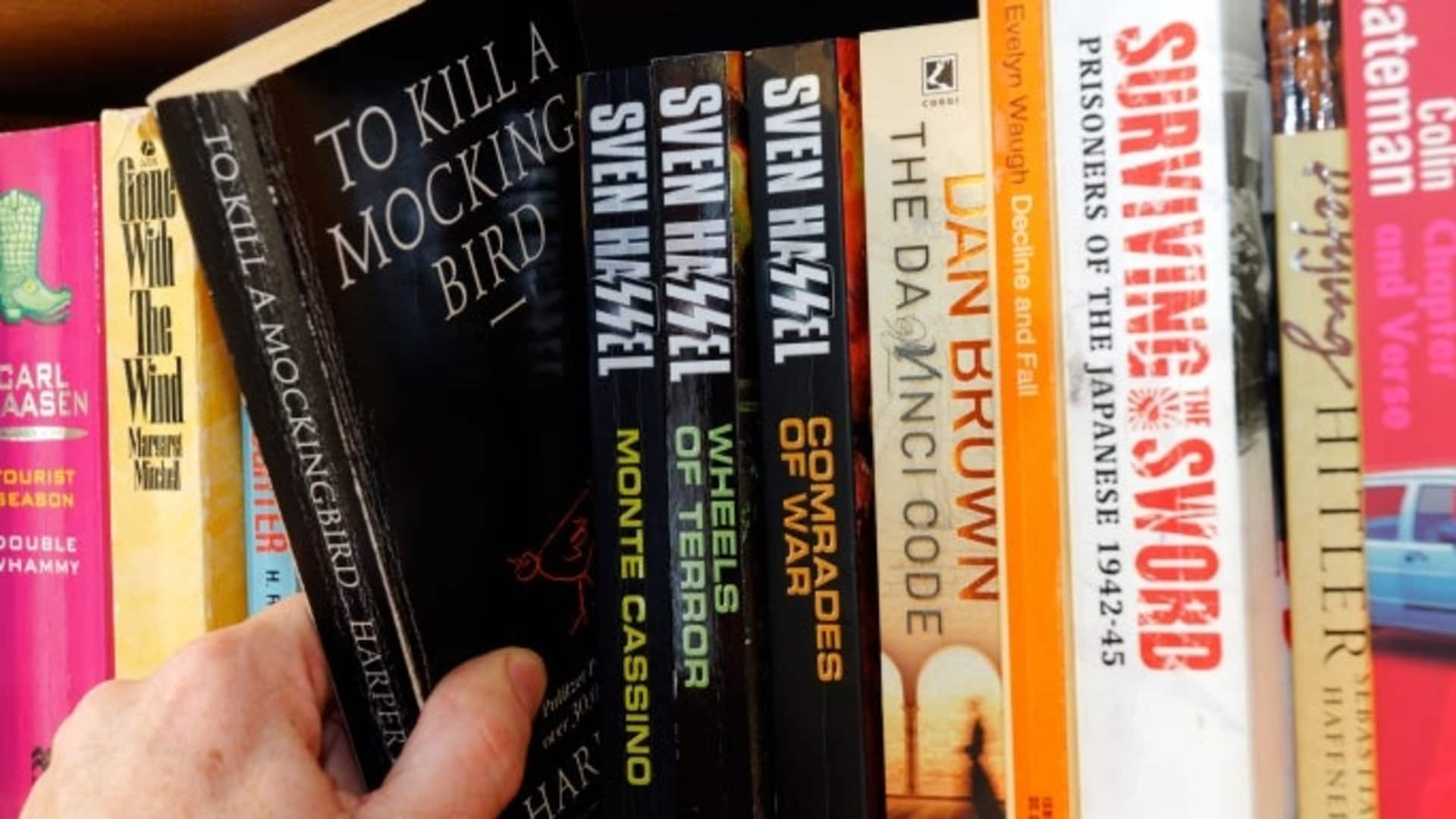 A copy of 'To Kill a Mockingbird' being pulled off a shelf.