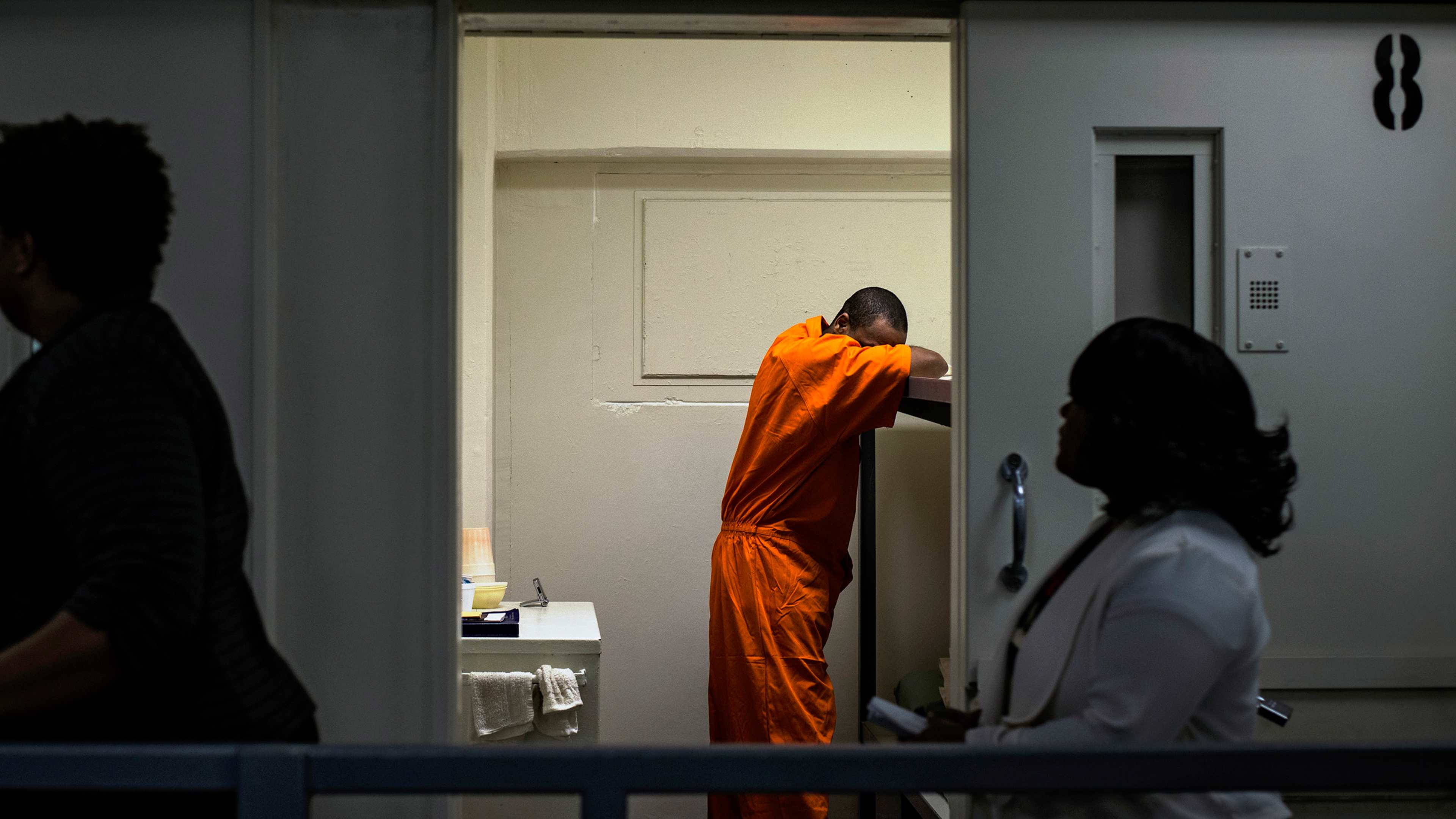 Members of DC Mayor Muriel Bowser's entourage walk past an inmate's cell as she tours DC Central Jail after announcing policy changes to support employment for inmates during and after incarceration in Washington