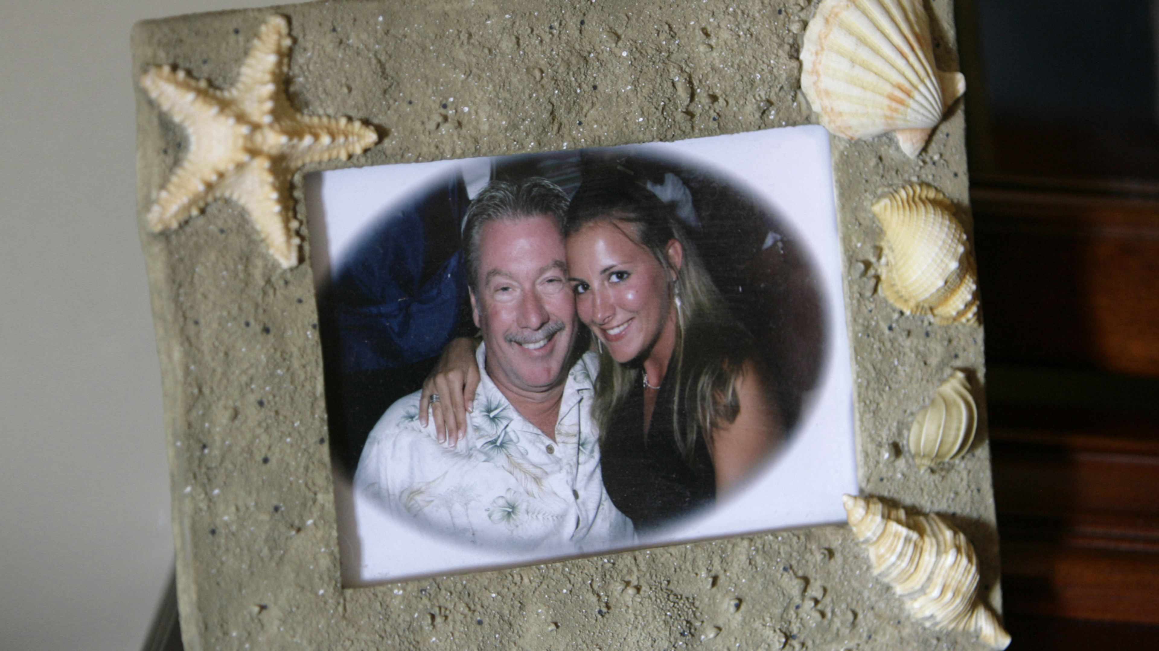 The image shows two smiling women in a photograph framed by seashells on a textured background.