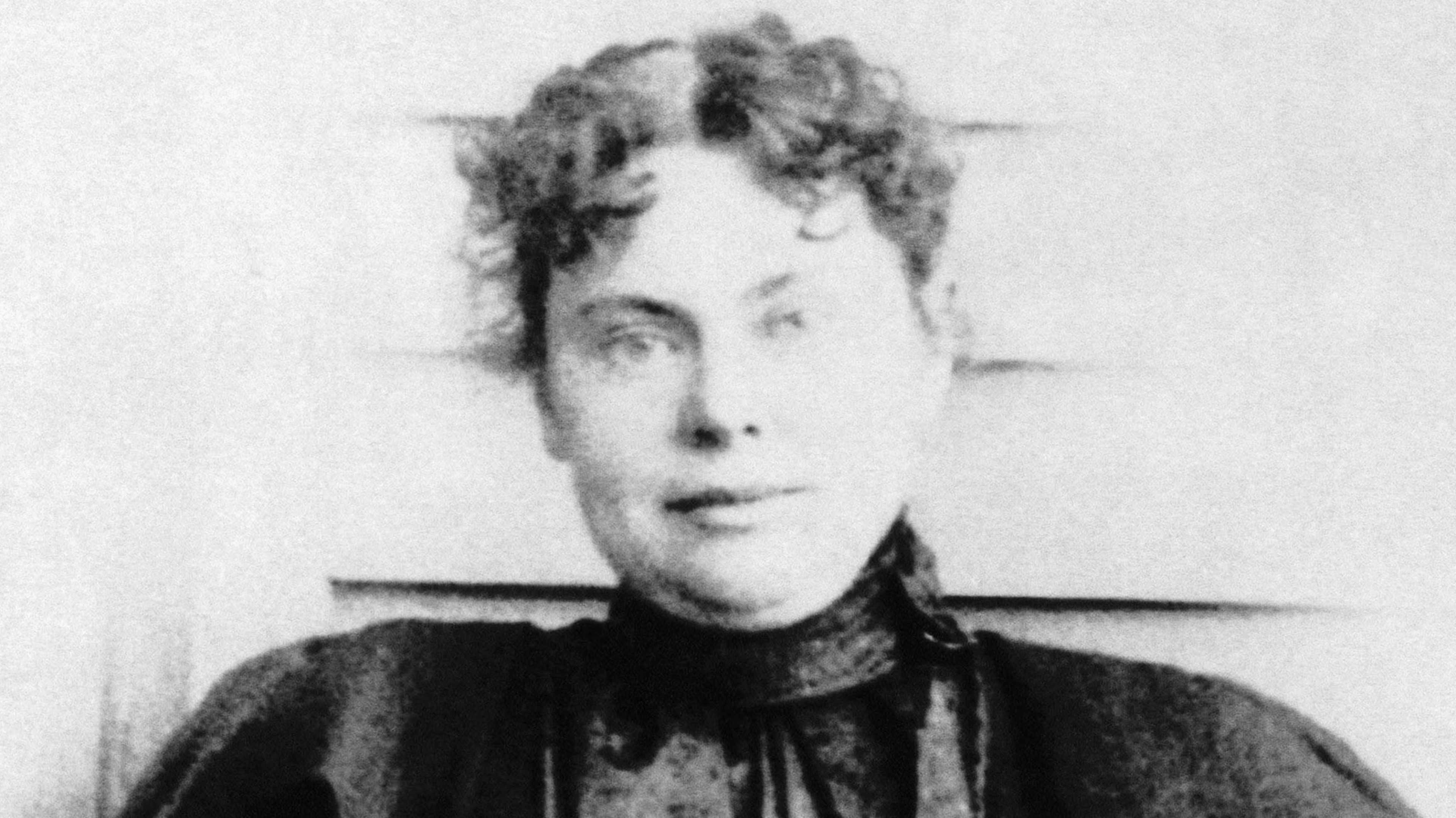 A black and white portrait of a person with a pensive expression, set against a blurred background.