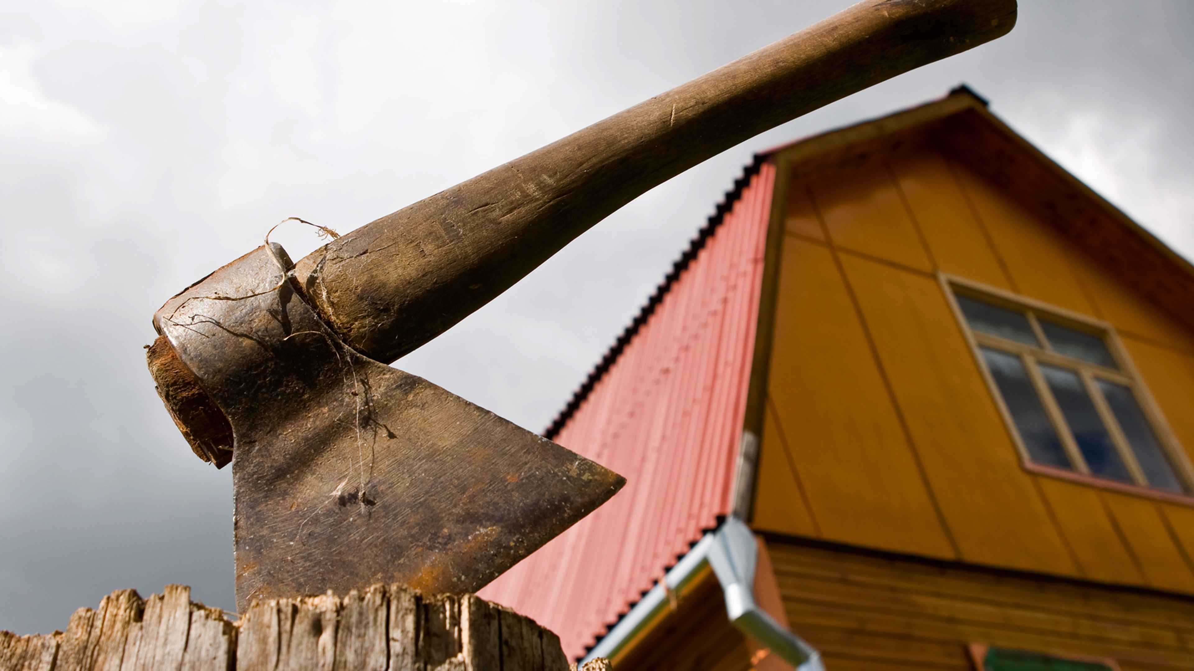Rusty ax. Country house in the background.