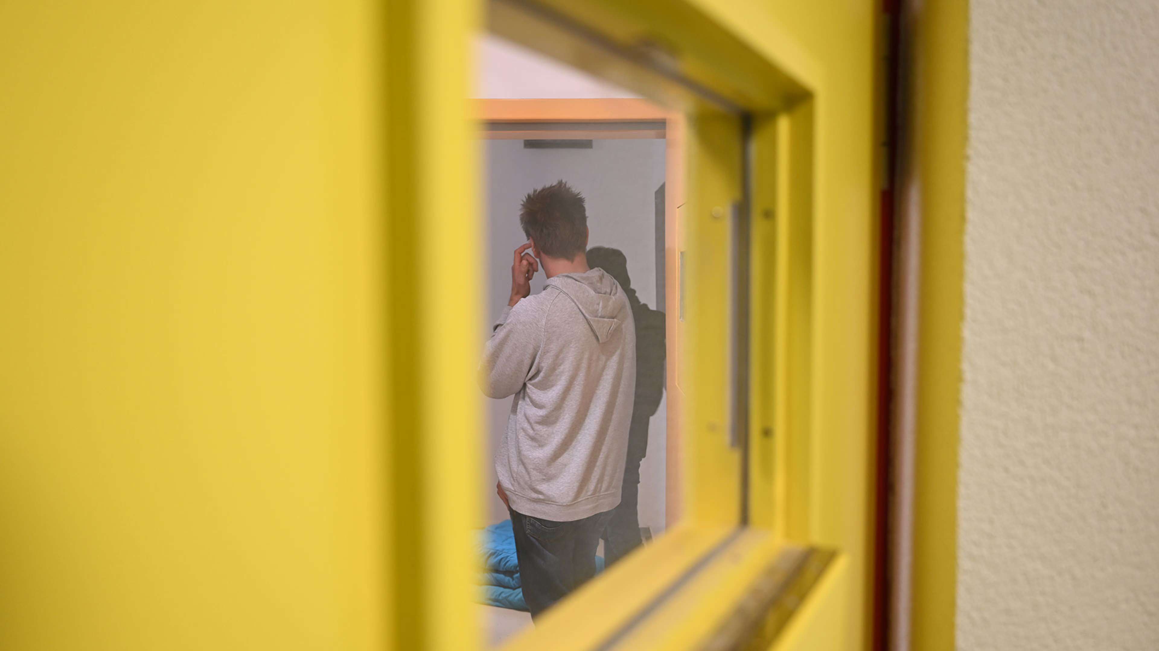 A person in a light-colored shirt is visible through a doorway framed by a yellow wall.