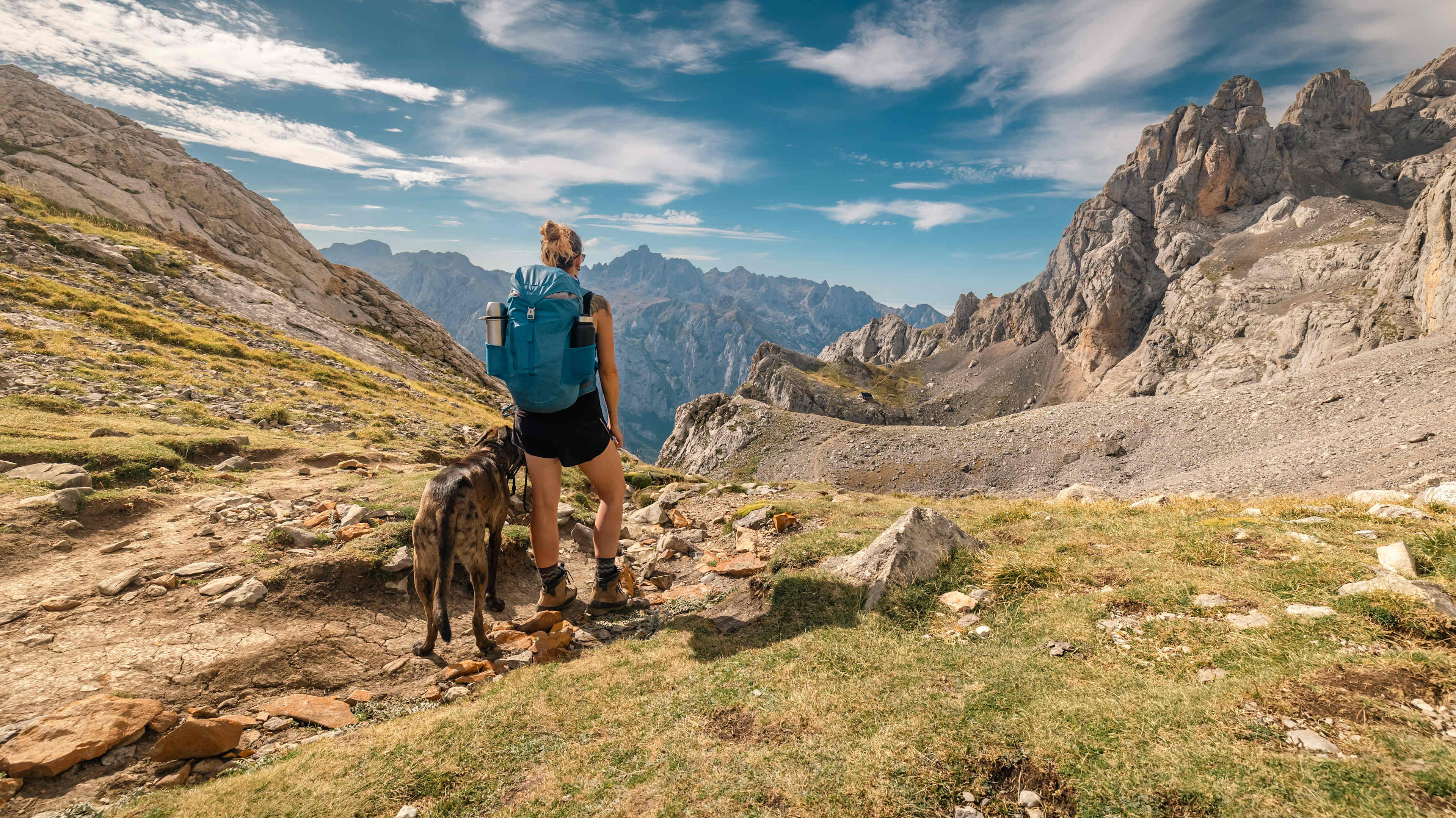 Young female hiker with a dog climbing in Picos de Europa National Park.