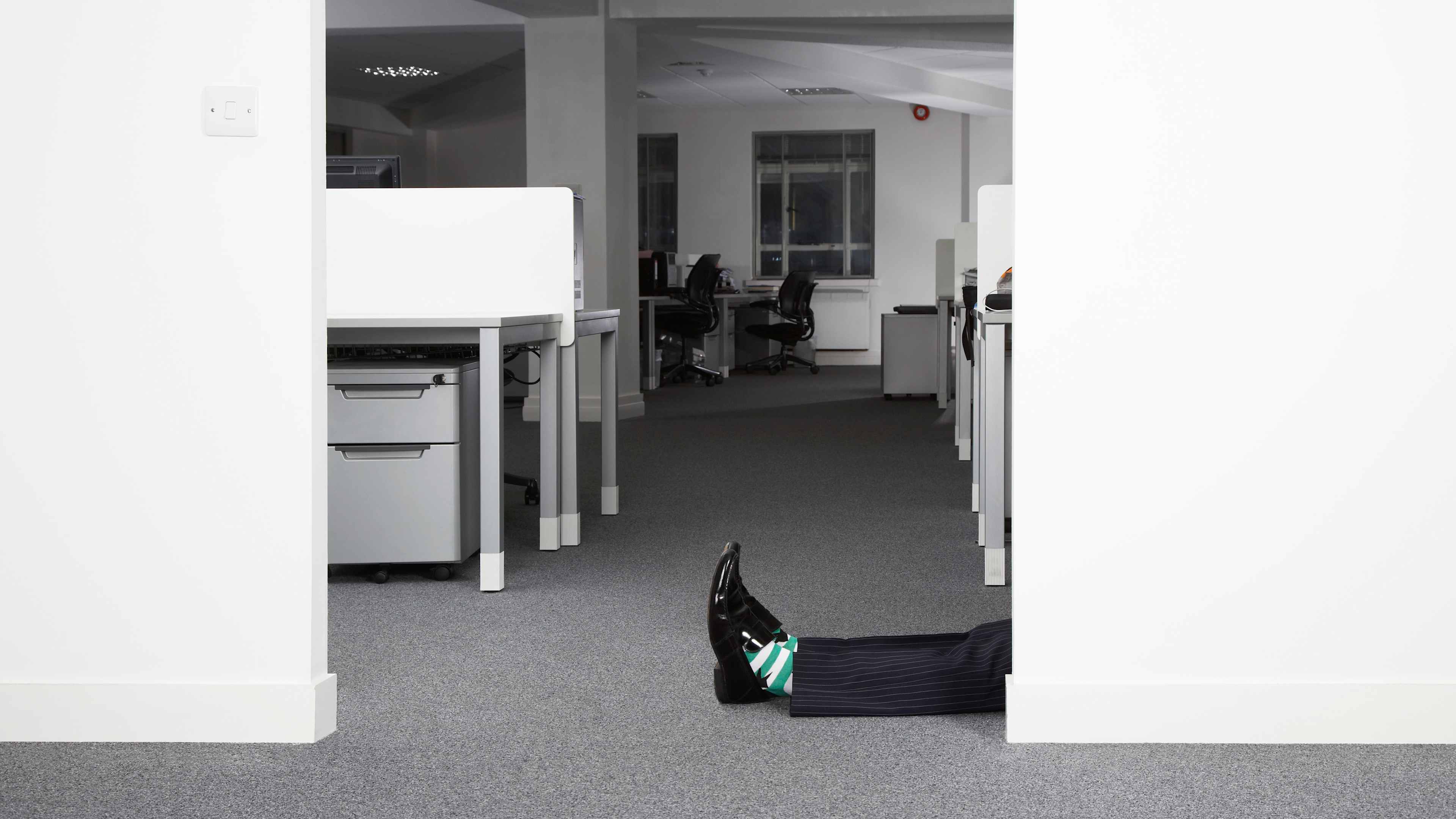 Man lying on floor in office, low section