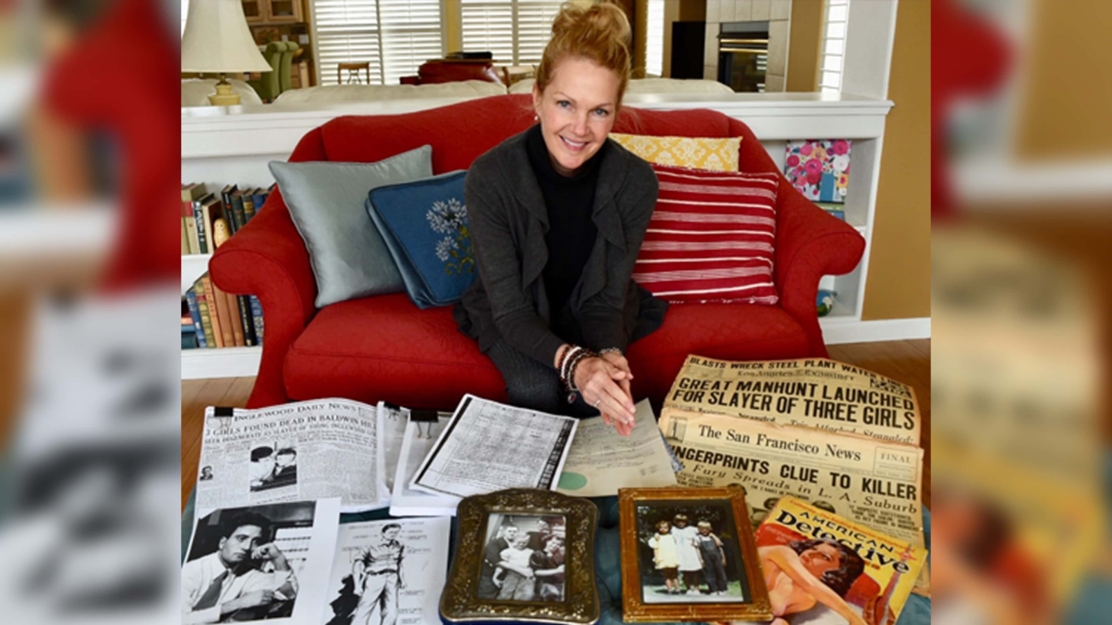 A woman with blonde hair sits on a red chair, surrounded by various items including books, photographs, and a newspaper headline about a killer.