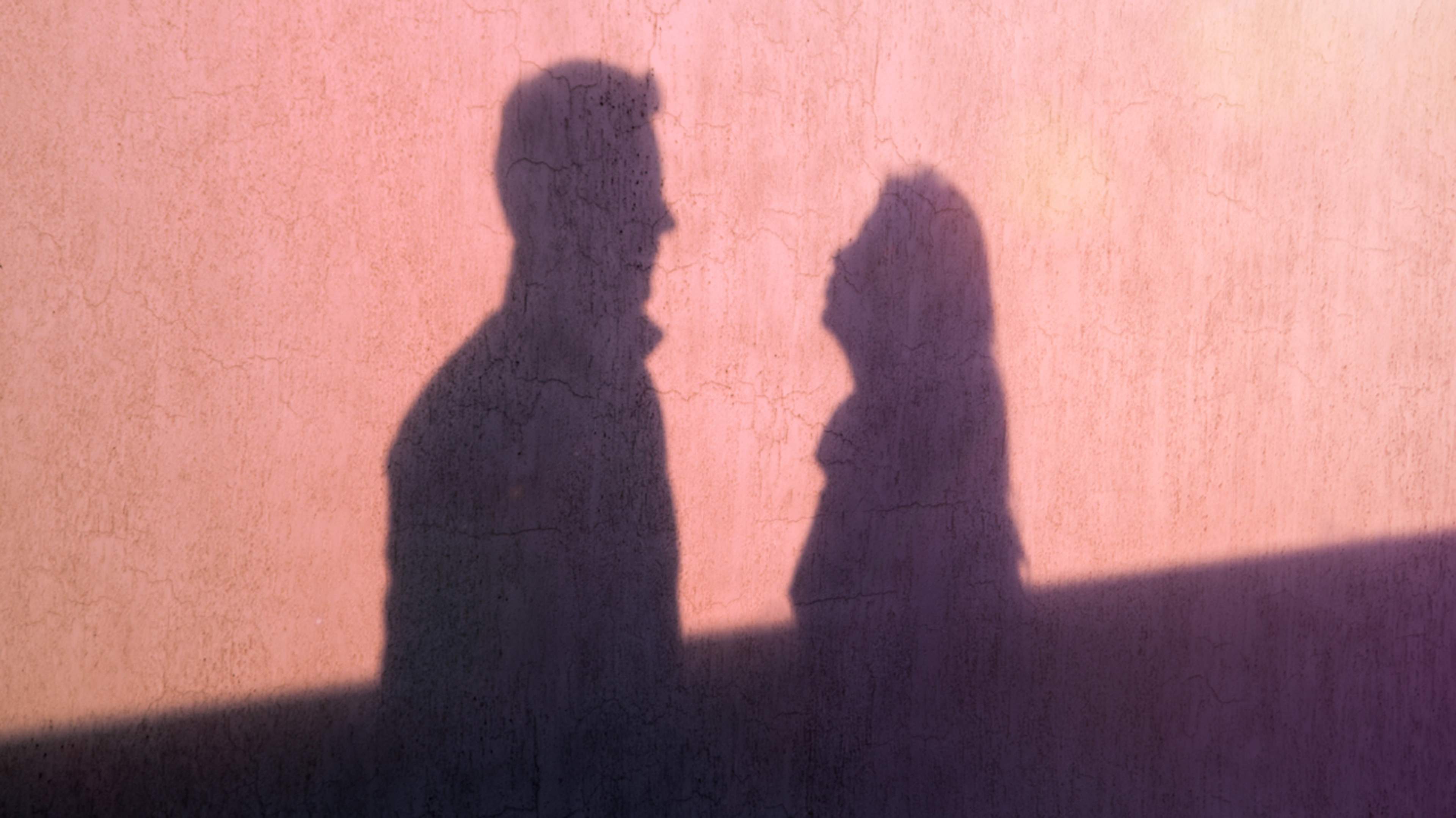 A talking couple silhouetted against a wall, facing each other.