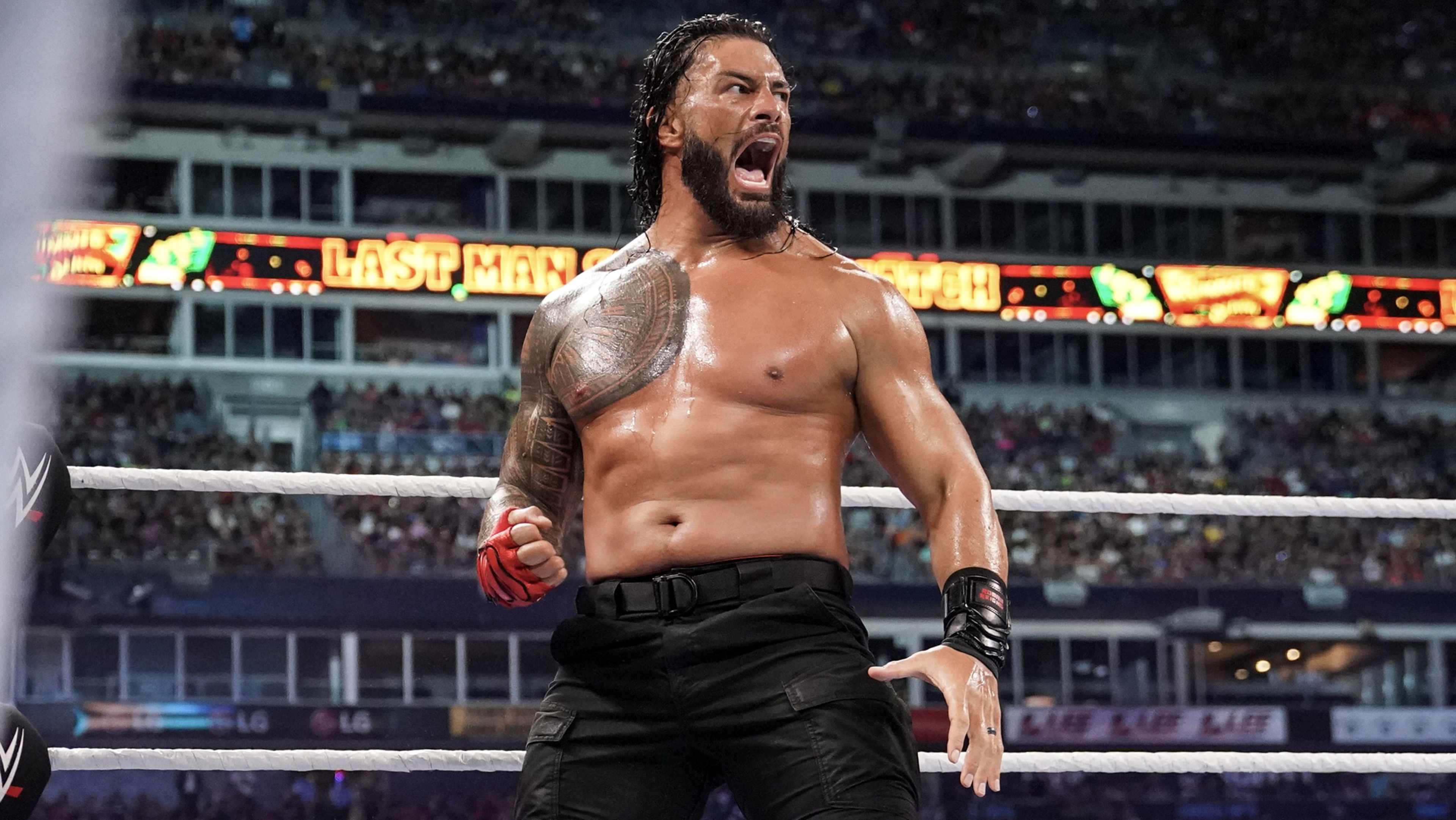 A muscular, shirtless man with tattoos stands in a wrestling ring, his face contorted in an intense expression.