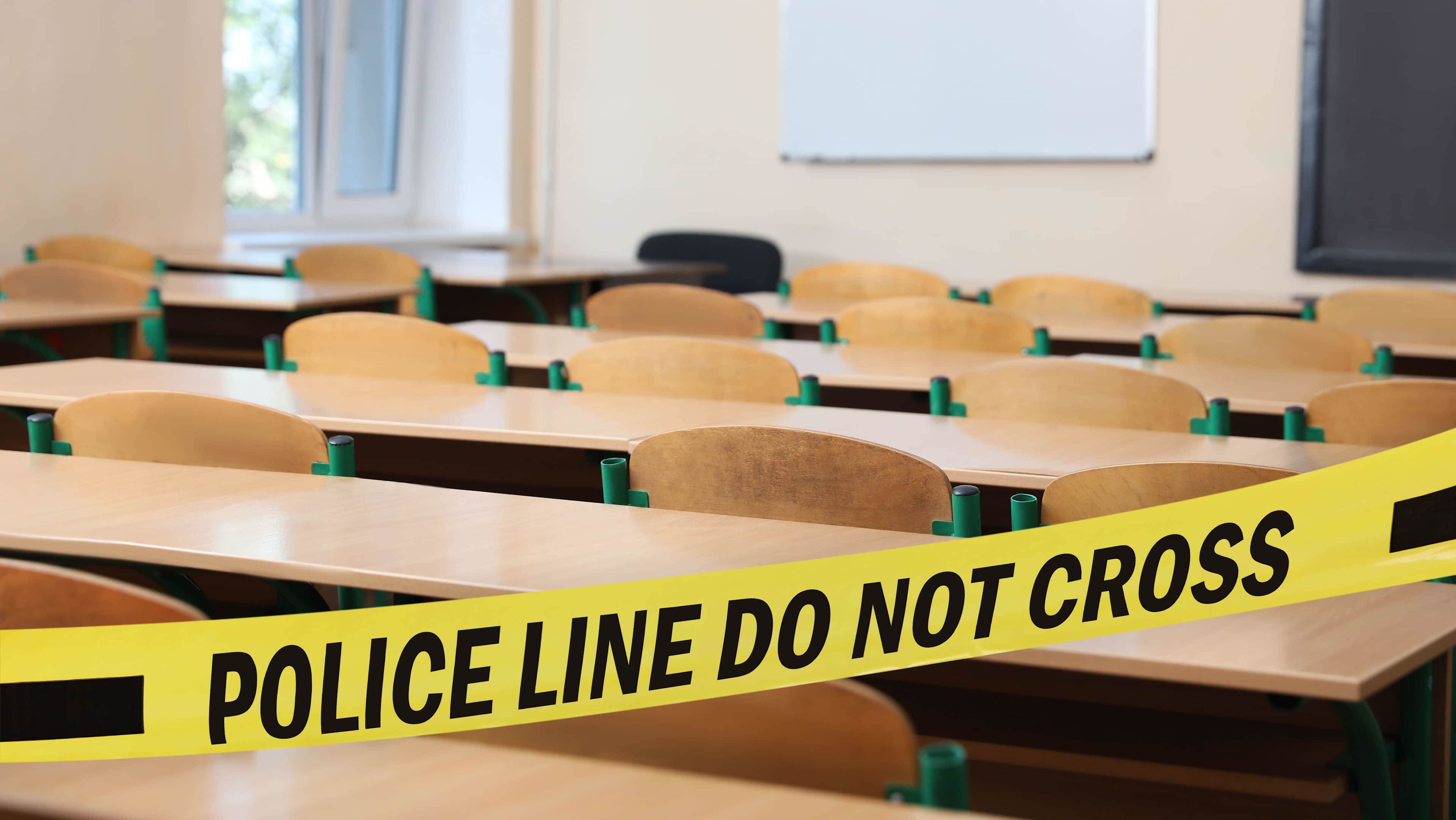 Yellow crime scene tape in empty school classroom