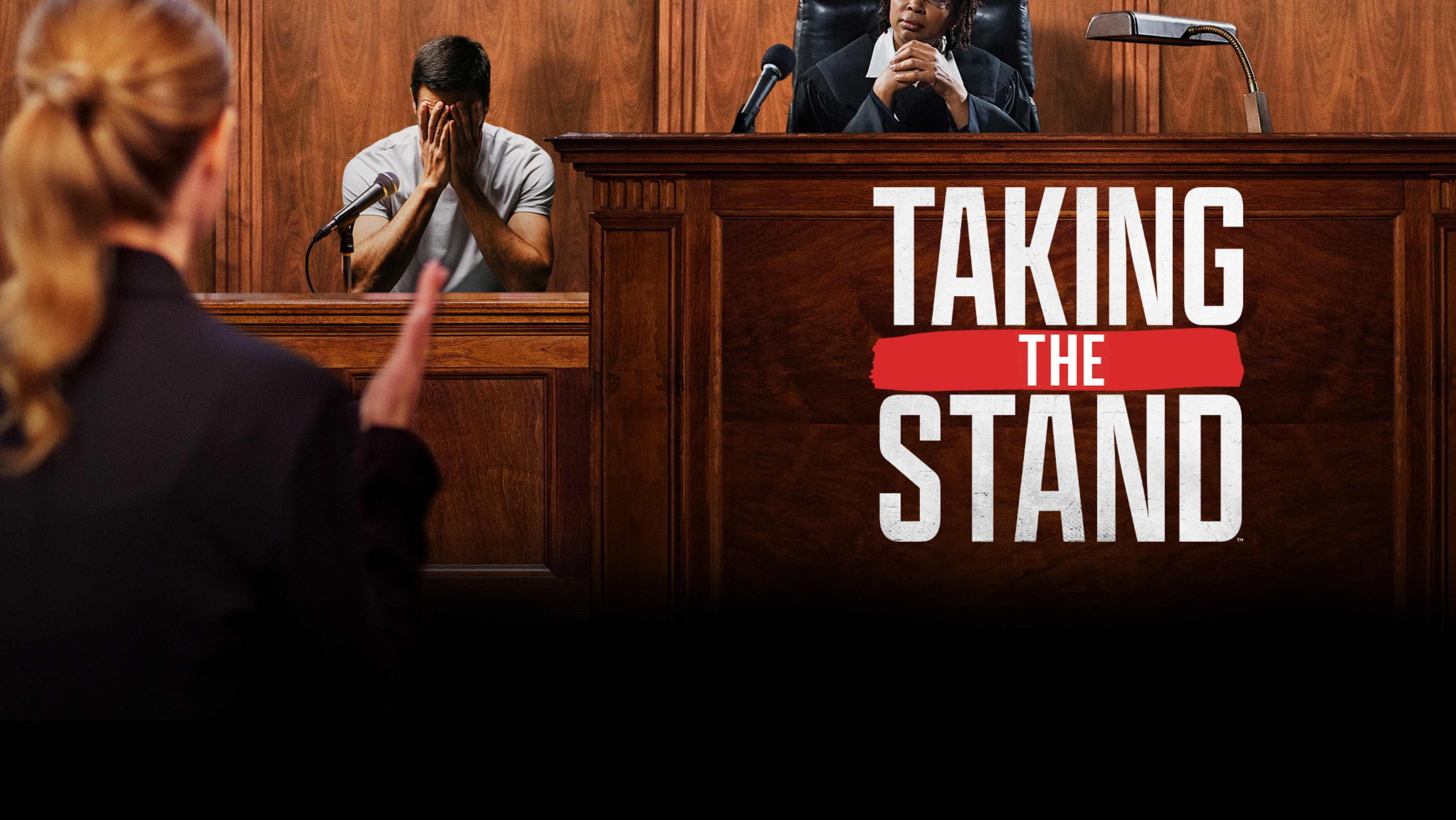 The image depicts a courtroom setting, with a person standing at a podium in the foreground and a large "TAKING THE STAND" sign visible in the background.