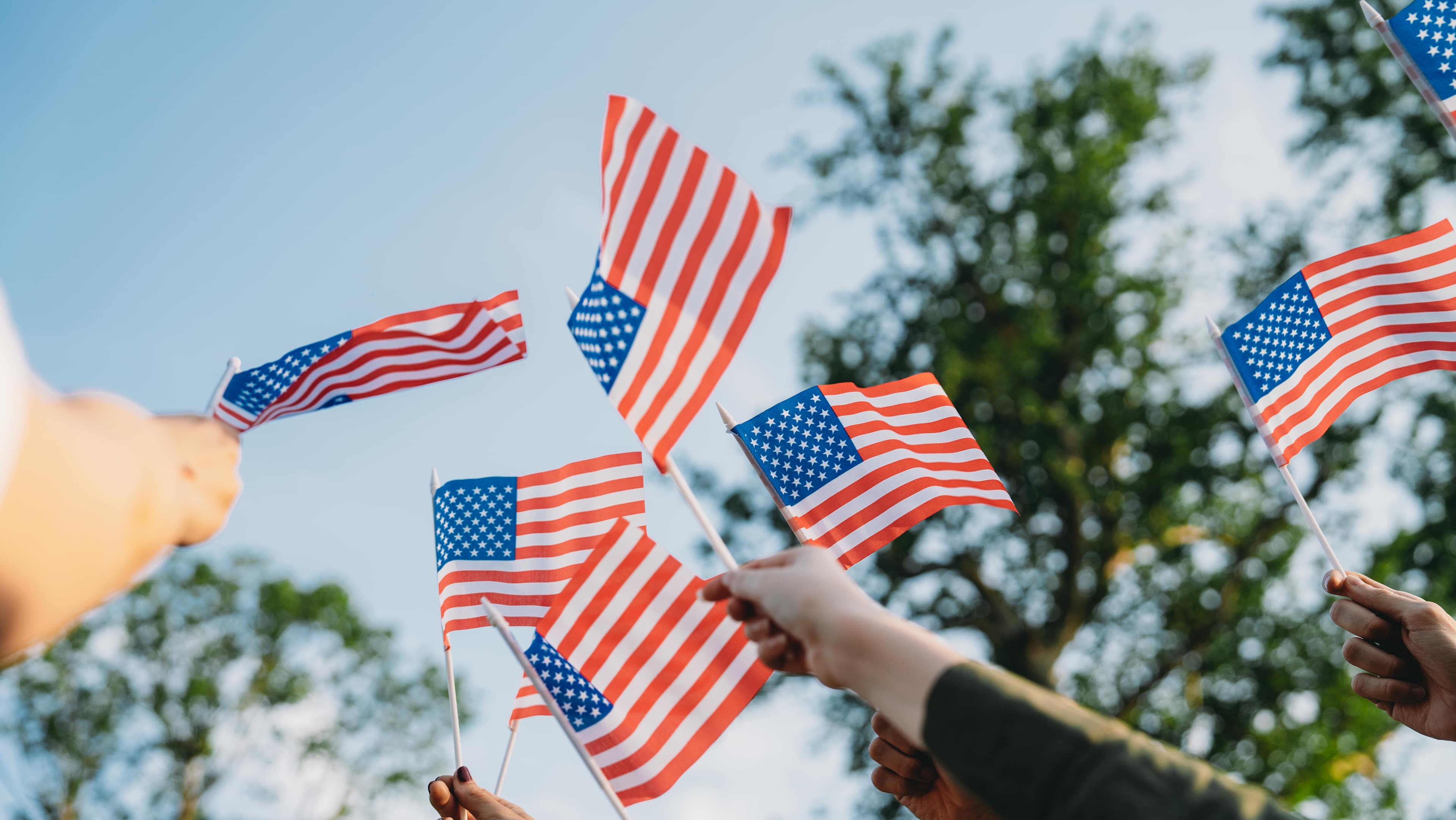 A group of people is waving small American flags at sunset