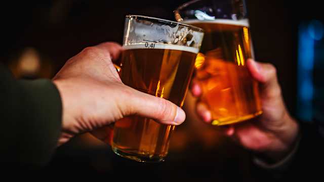 Two friends hands toasting with glasses of craft beer at the pub or bar. taproom