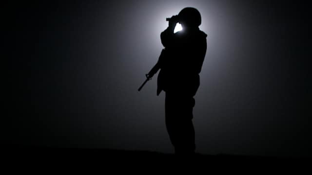 A Marine from the 3rd Battalion, Fourth Marines scans the horizon with night vision goggles while silhouetted by the moon during midnight patrol around Camp Mercury, the former Camp Abu Ghraib, June 23, 2005 in Anbar province, Iraq.
