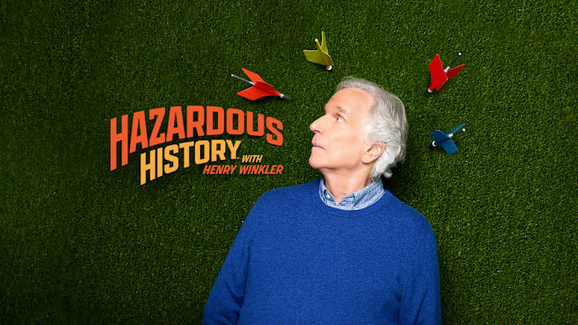 An elderly person with gray hair stands in front of a green grassy background, with a book cover titled "Hazardous History" by Henry Winkler displayed prominently.