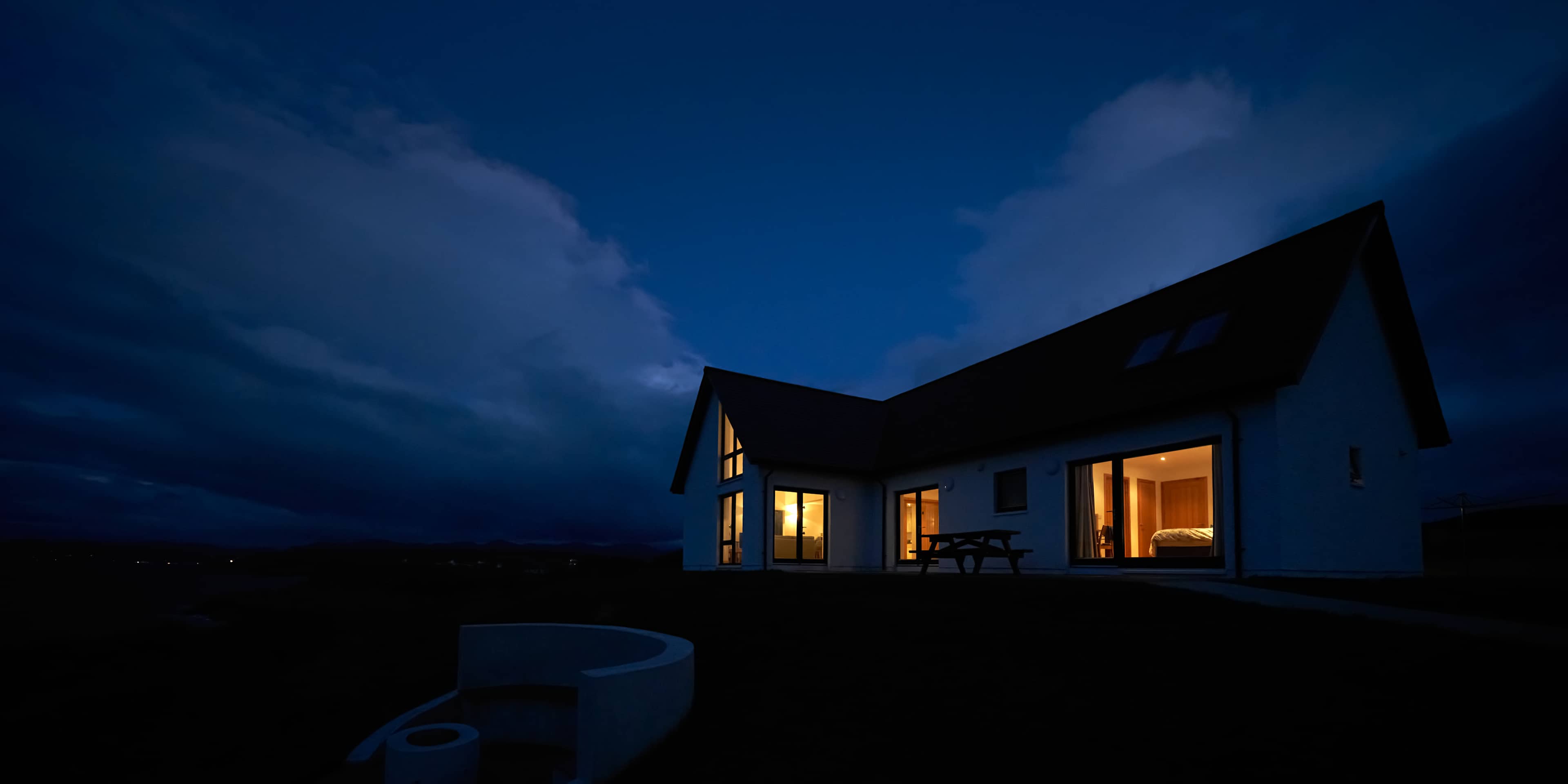 The warm glow of lit rooms from a remote Scottish Highland croft at night