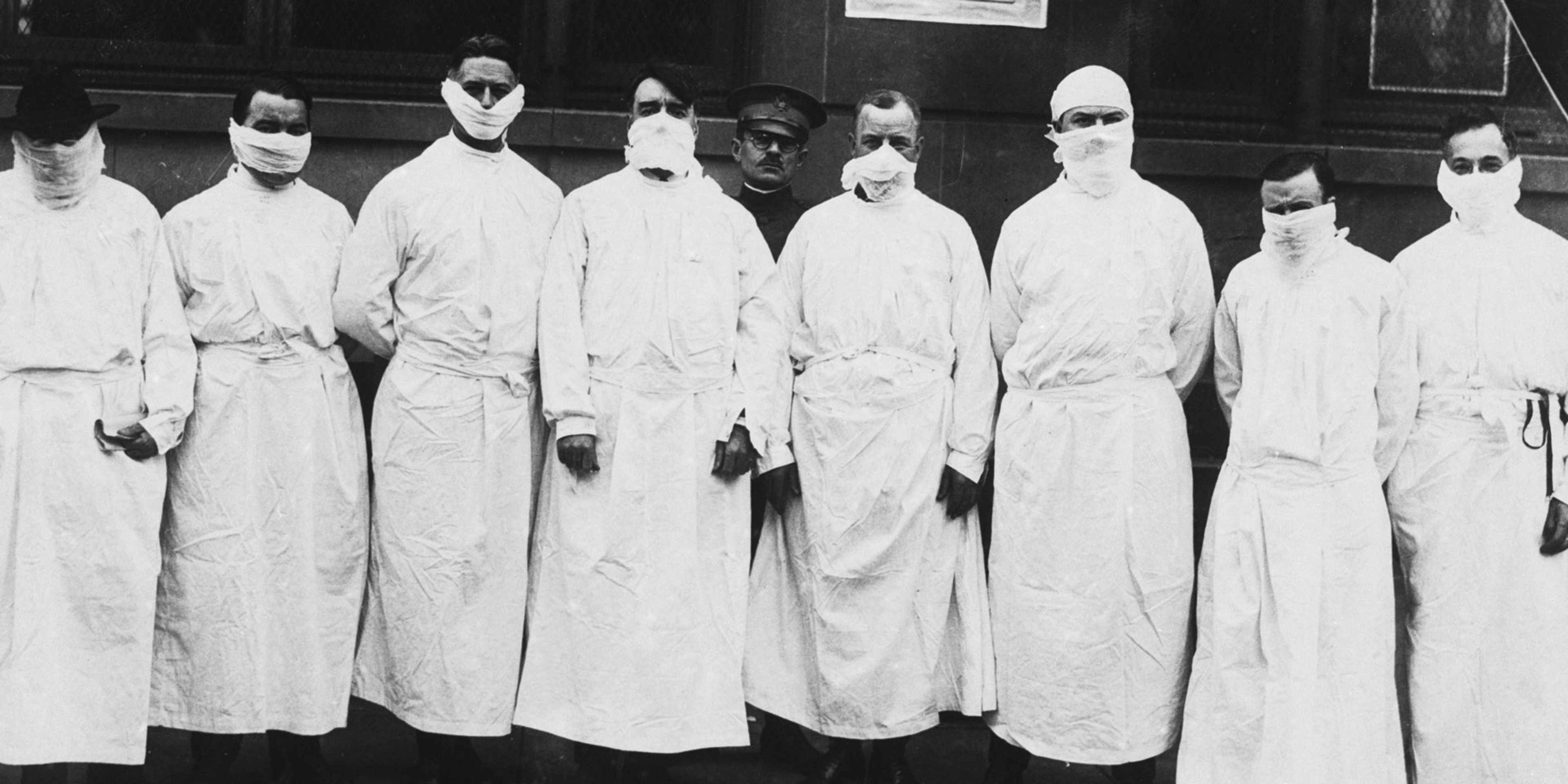 Doctors, army officers, and reporters wear surgical gowns and masks at a hospital to observe Spanish influenza treatment of patients