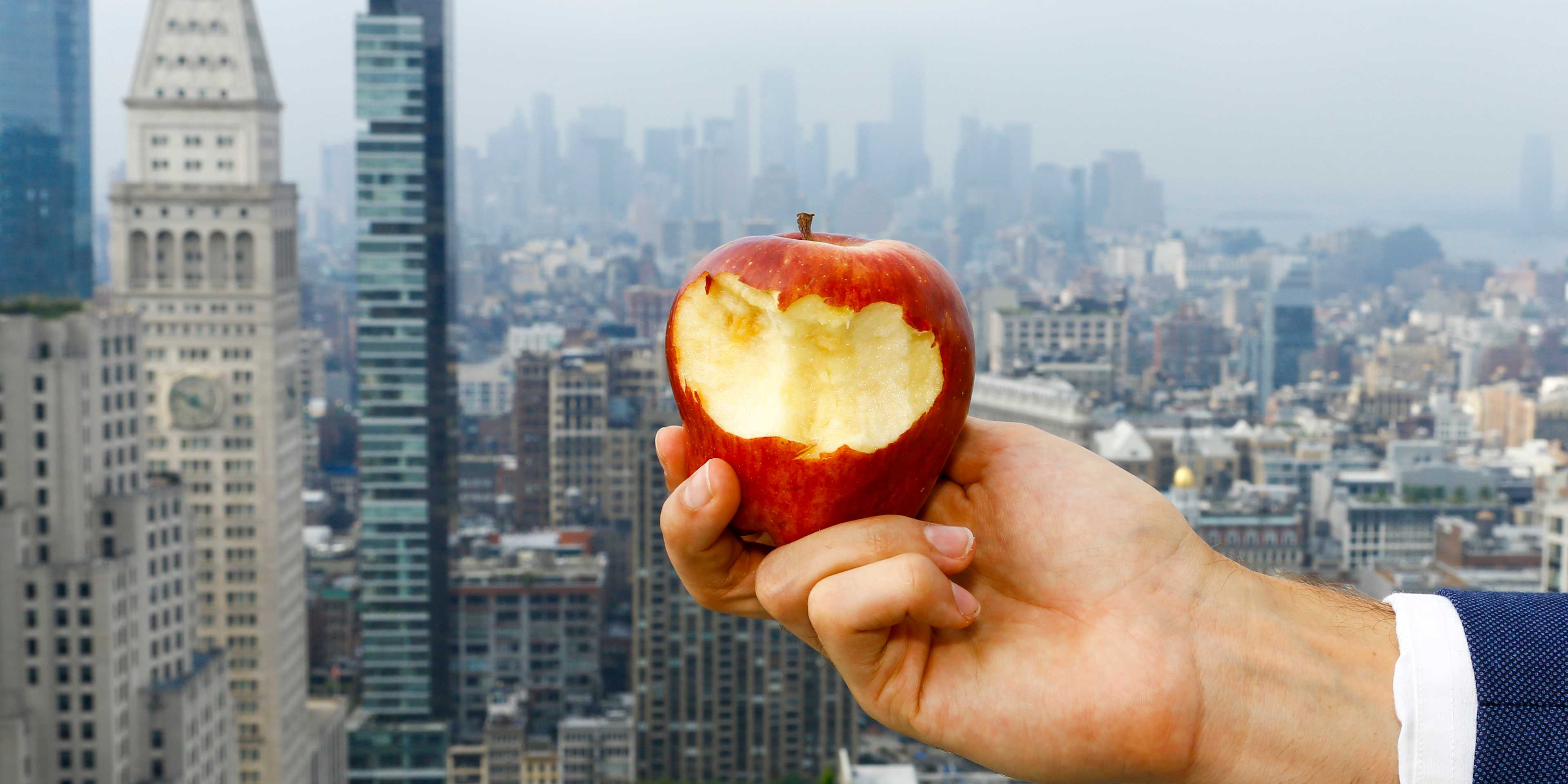 Hand of Caucasian man holding bitten apple on urban rooftop
