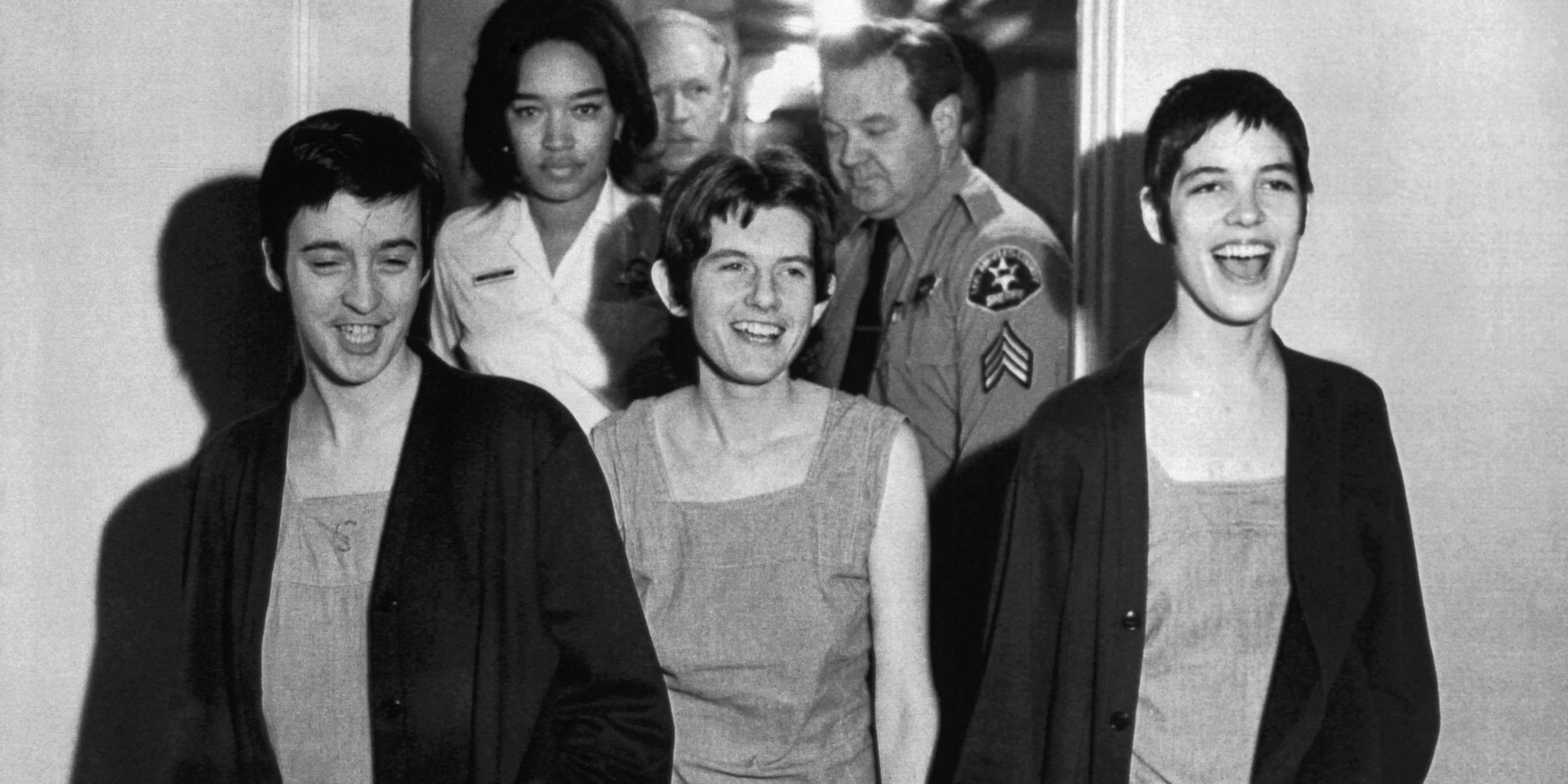 A group of people, some smiling and others with serious expressions, are gathered together in what appears to be a formal setting, possibly a military or government office.