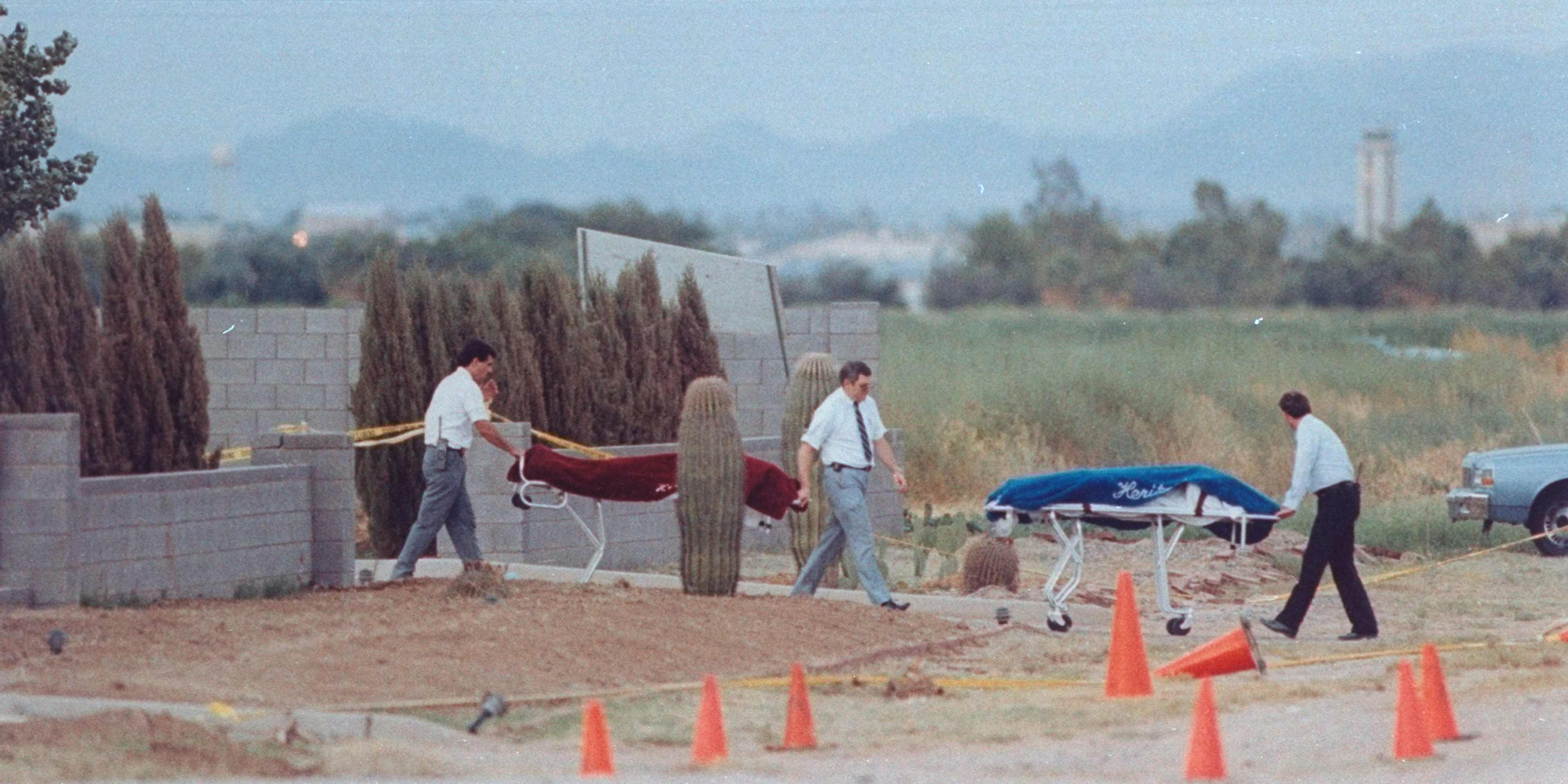 The image shows several people engaged in various activities on a construction site, with a mountainous landscape visible in the background.