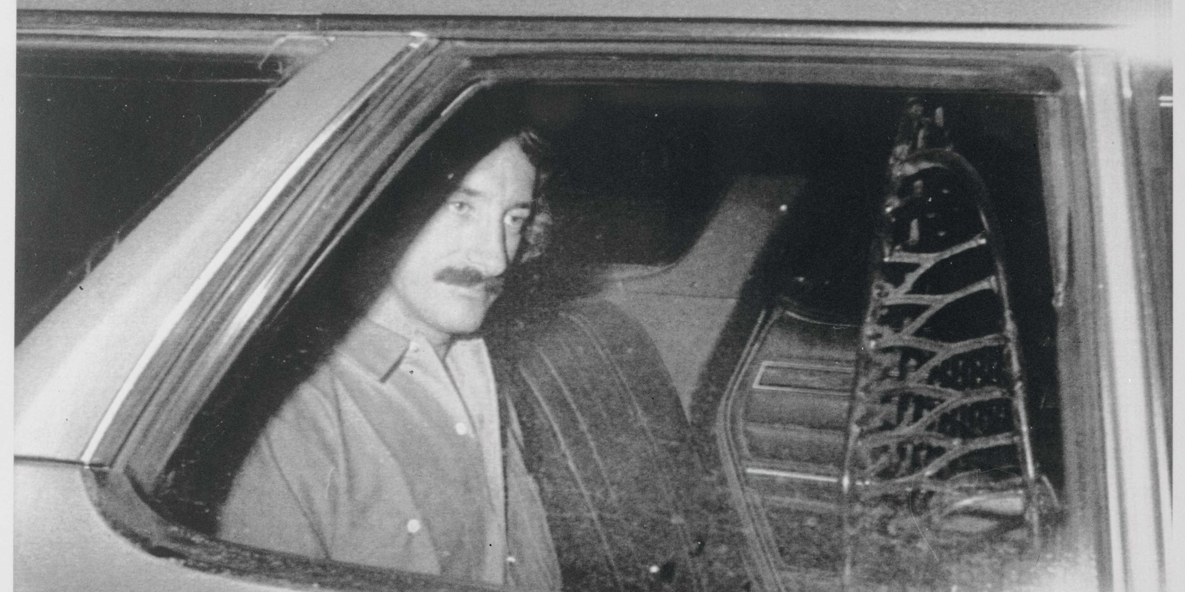 A person is visible through the window of a vehicle, with a background that appears to be a snowy or wintry scene.