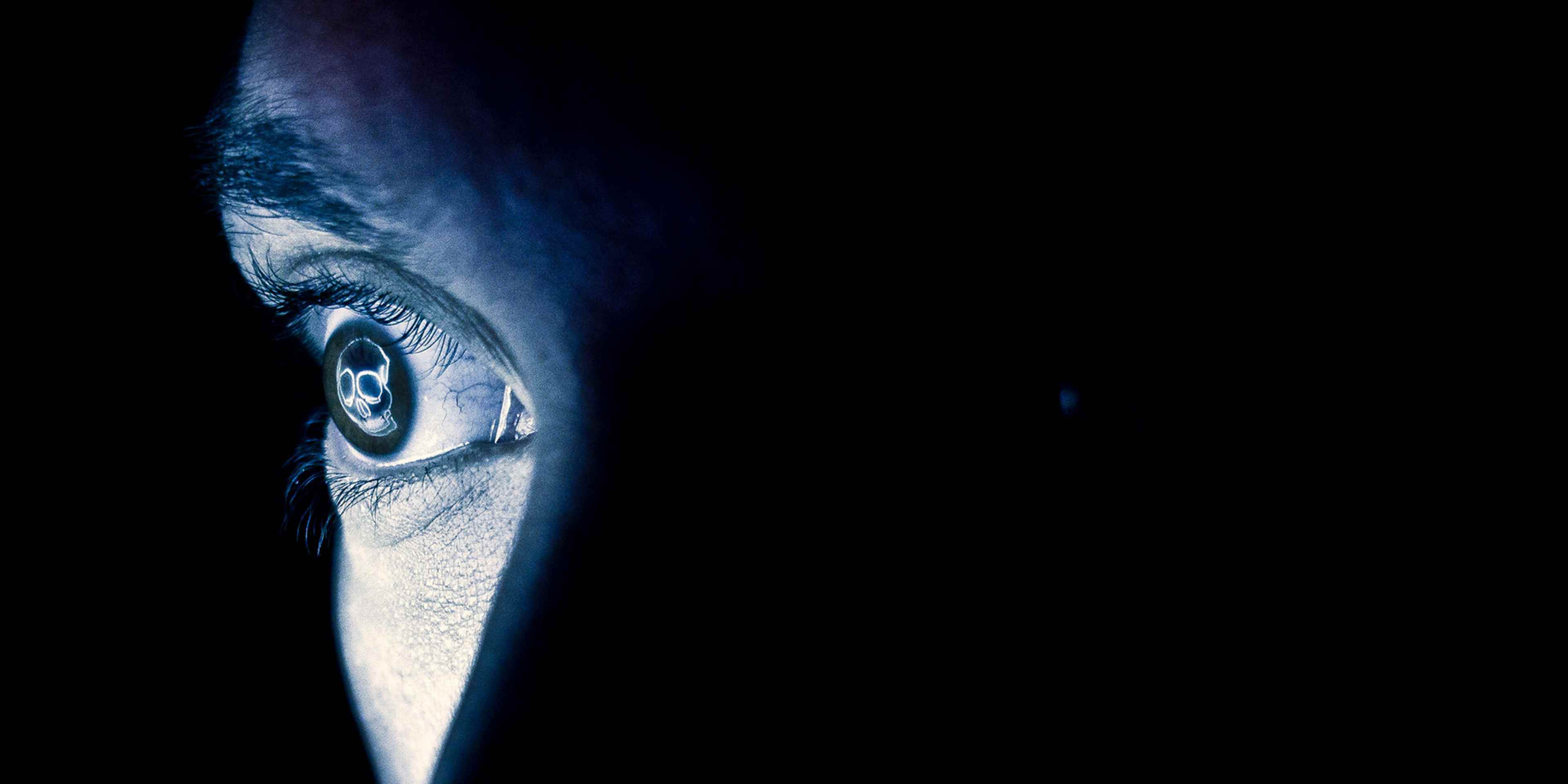 A close-up view of a human eye, with its intricate details and vibrant blue hue, set against a dark, mysterious background.