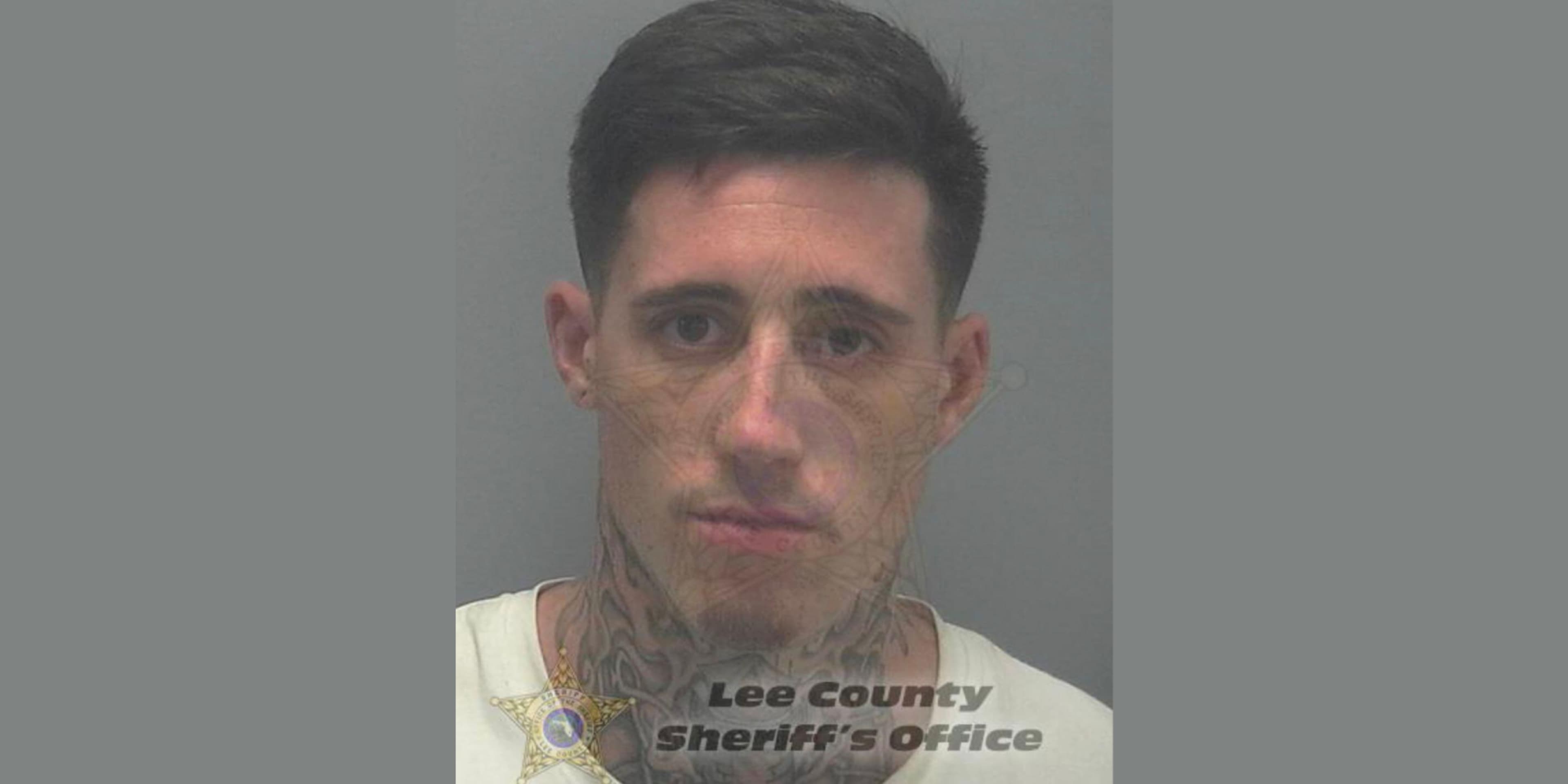 The image shows a close-up portrait of a man with a serious expression, wearing a white shirt and a badge indicating he is from the Lee County Sheriff's Office.