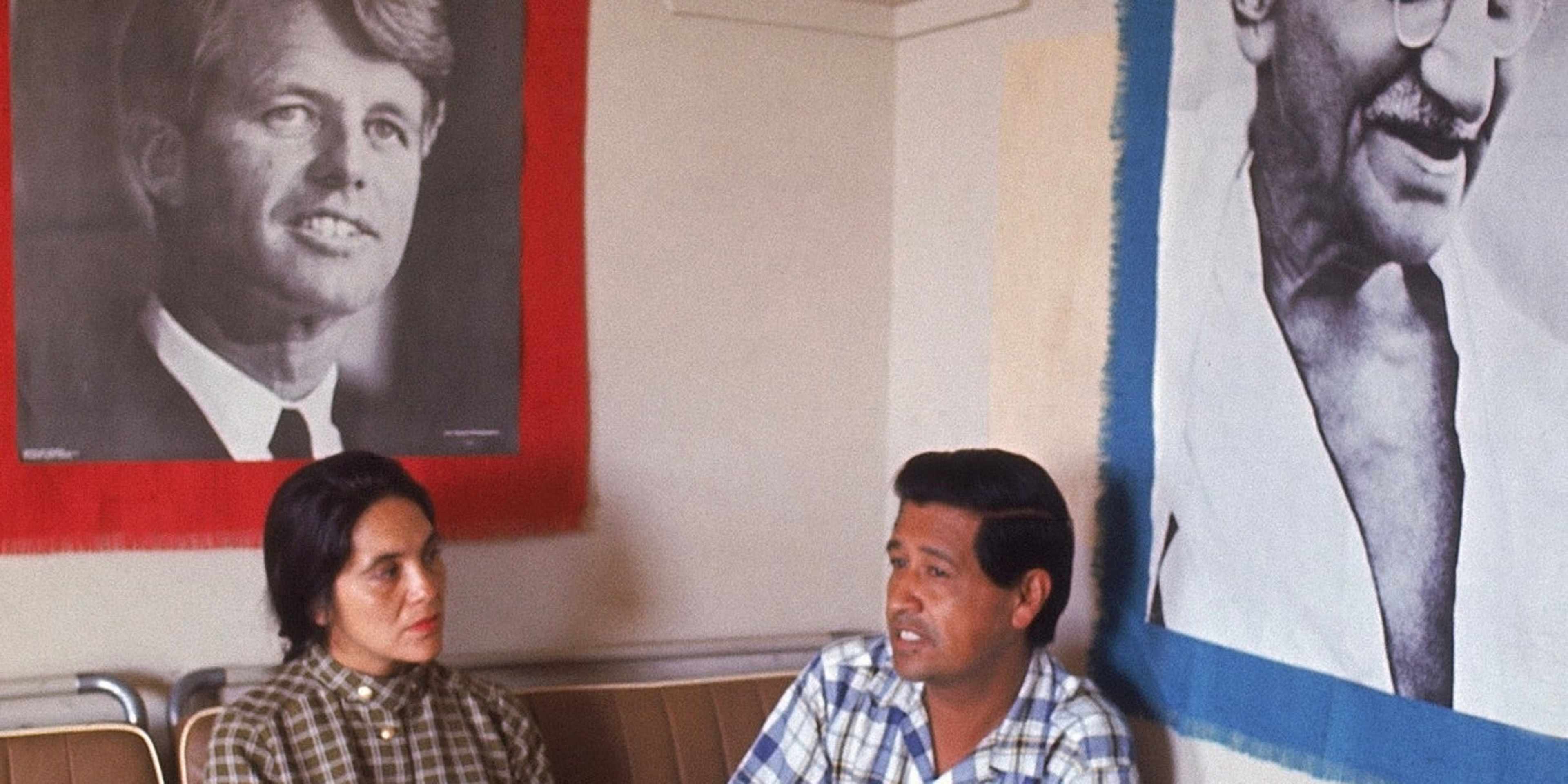 United Farm Workers co-founders Dolores Huerta and Cesar Chavez sit together under portraits of Robert Kennedy and Mahatma Gandhi.