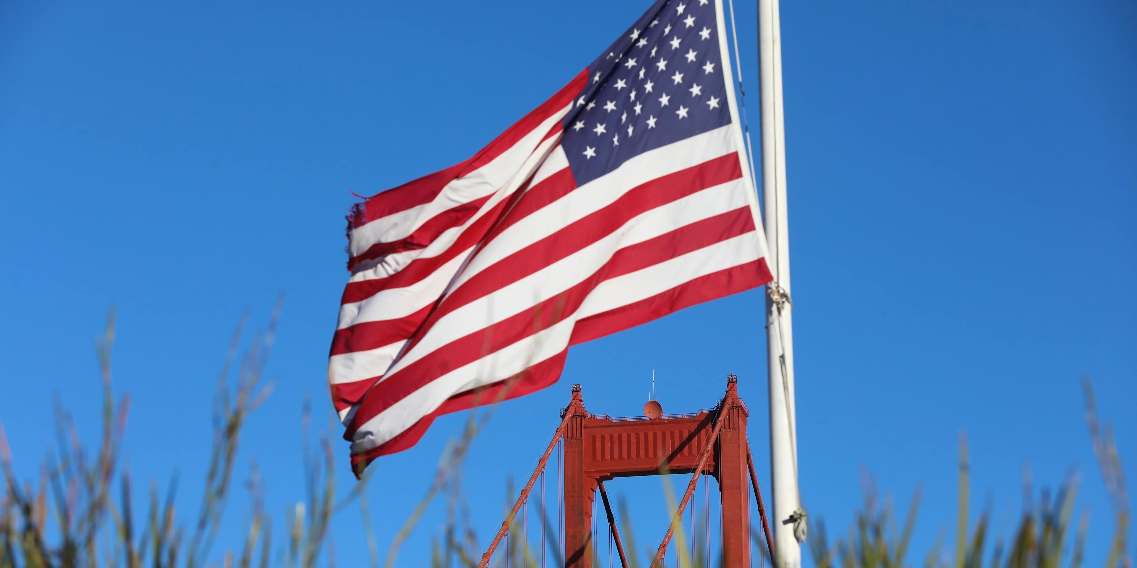 An American flag near the Golden Gate Bridge in San Francisco, California, US, on Monday, Jan. 23, 2023. A $400 million federal grant to upgrade and retrofit the Golden Gate Bridge to ensure it can withstand the impacts of a major earthquake was unveiled following the passage of the bipartisan infrastructure law in Congress last year that included funding to repair and rebuild bridges across the country. Photographer: Benjamin Fanjoy/Bloomberg via Getty Images