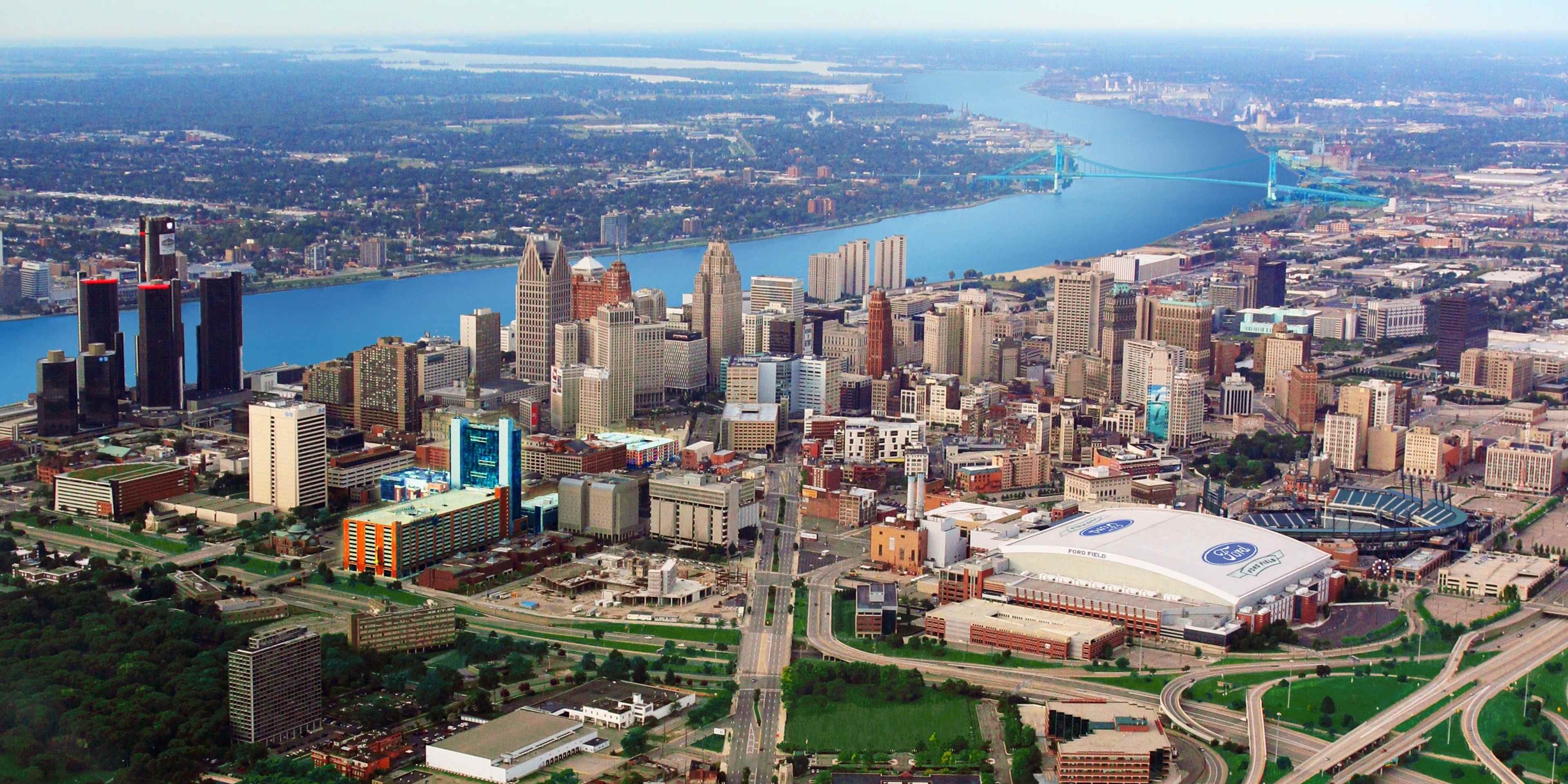 This aerial view, shot from low altitude in a small plane, shows most of downtown Detroit, Michigan. Included in the shot is Ford Field, home of the Detroit Lions, Comerica Park, home of the Detroit Tigers, the Ambassador Bridge, and the Detroit skyline. The Detroit River bisects the image.