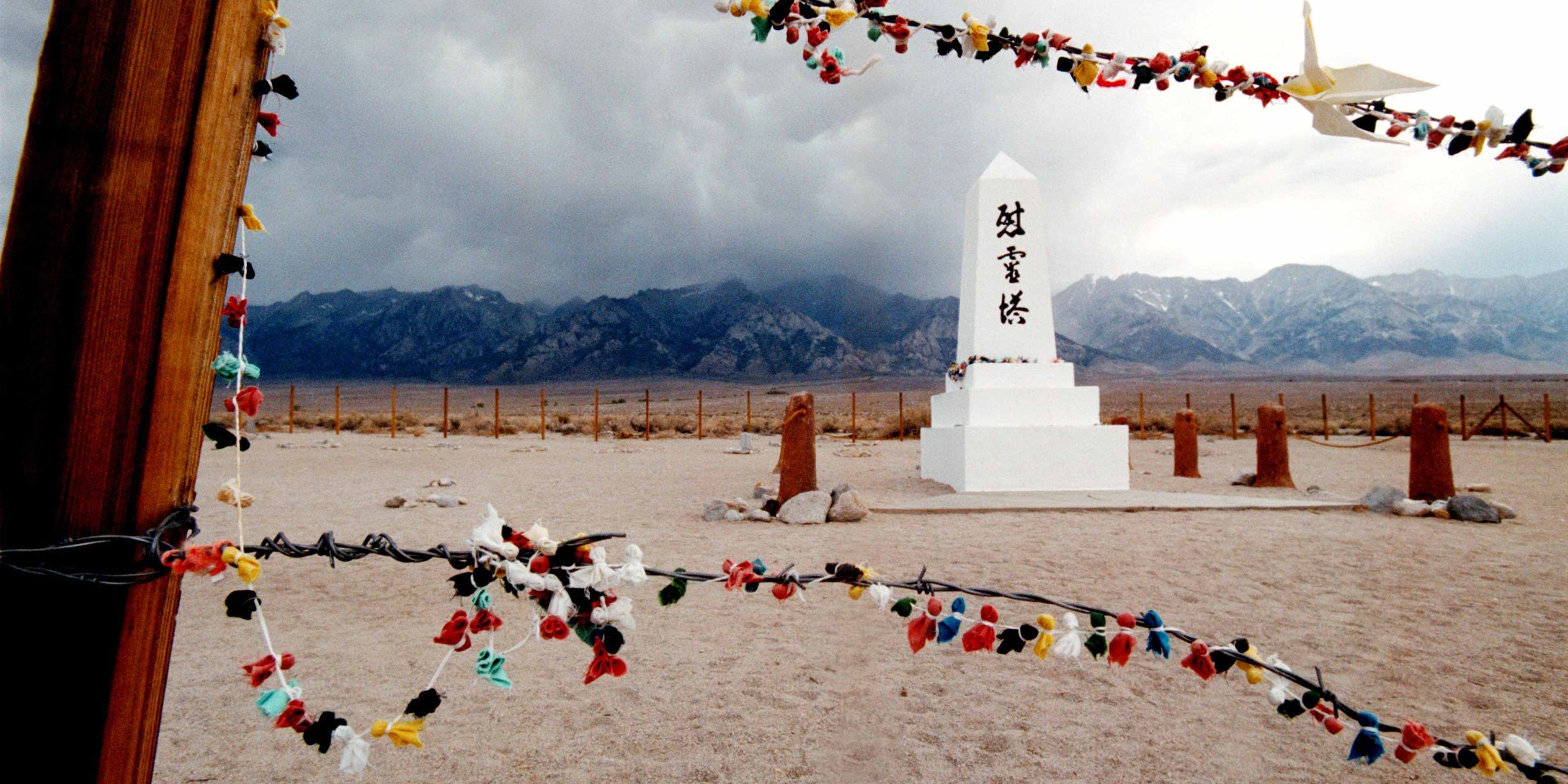Offerings hanging on the barded wire fence surrounding the cemetery of the Manzanar War Relocation Center in 2000. Manzanarn served as an internment camp for 10,000 Japanese-American citizens and Japanese aliens during World War II after the bombing of Pearl Harbor. The National Park Service maintains Manzanar as a national historic site. (Credit: David McNew/Newsmakers/Getty Images)