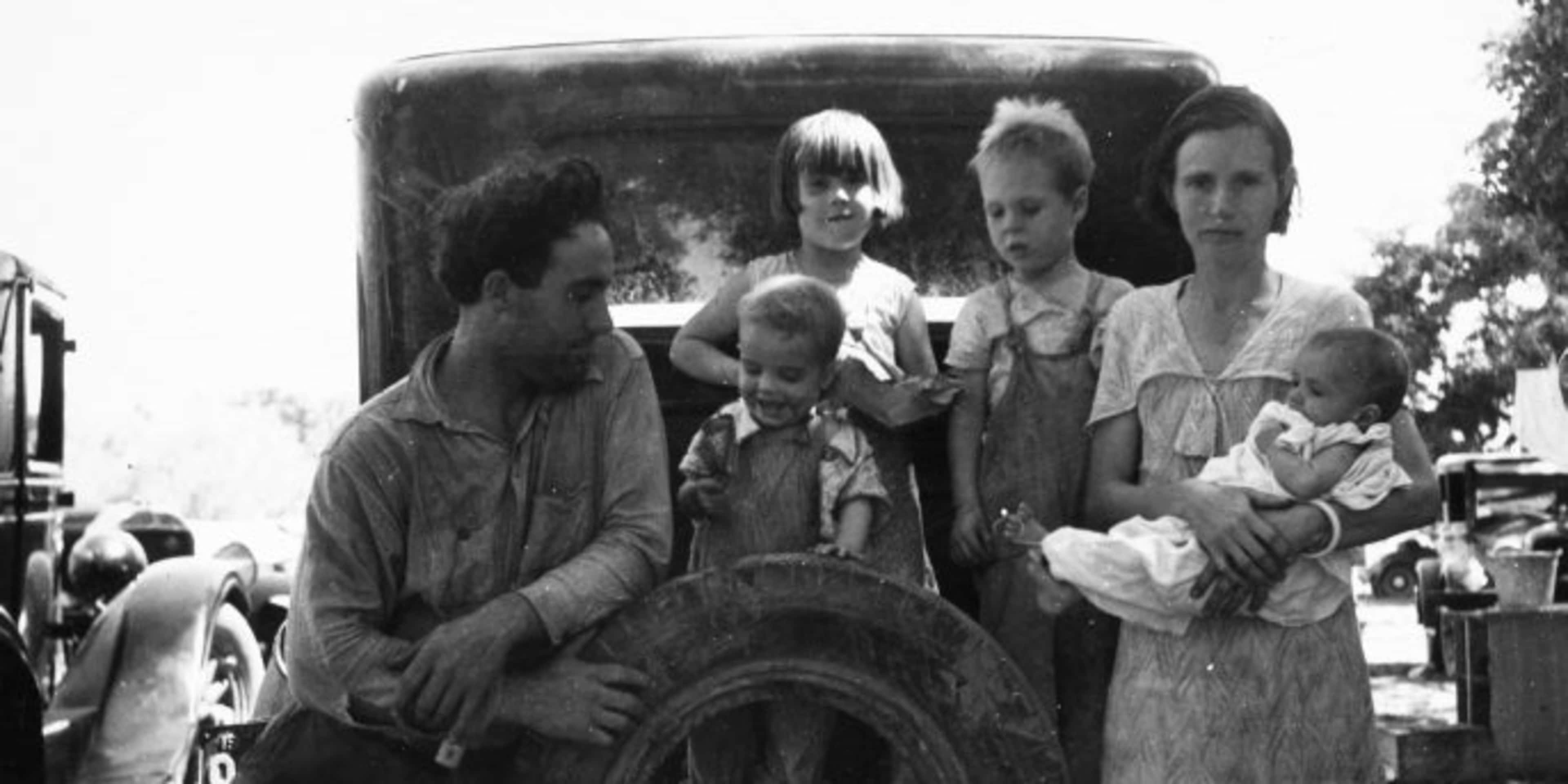 A migrant worker with his wife and four small children, resting on the back of a car in Marysville, California, 1935. (Credit: Smith Collection/Gado/Getty Images)